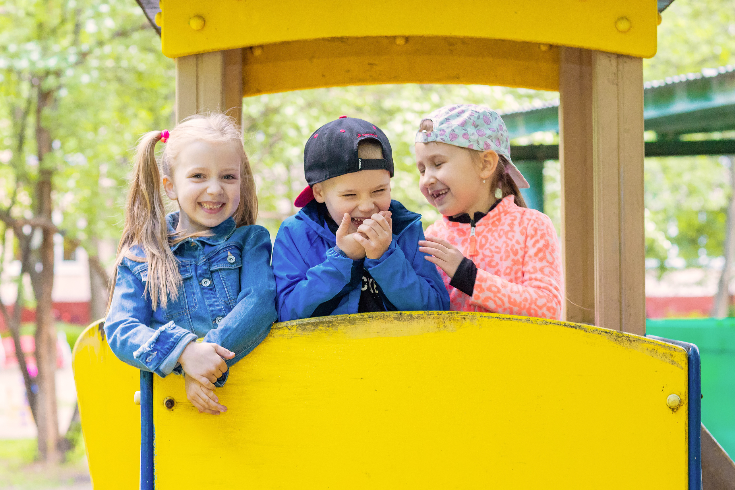 Дети на улице в детском саду сидят в машинке