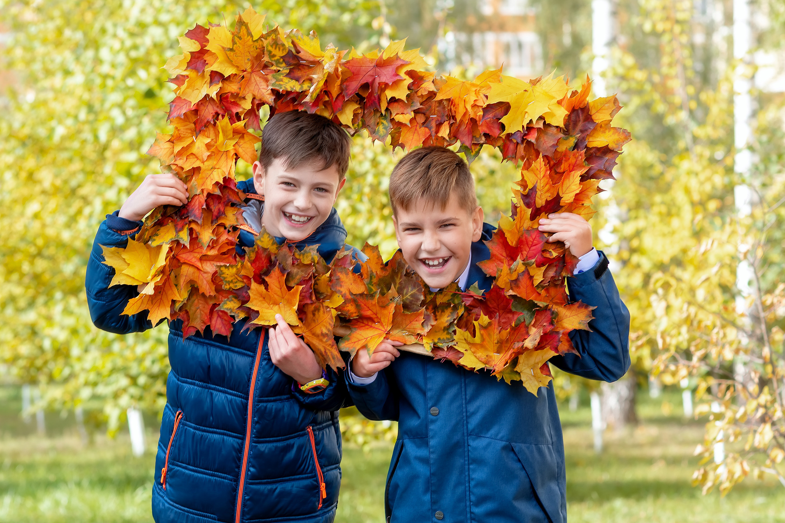 Два мальчика позируют осенью во дворе школы