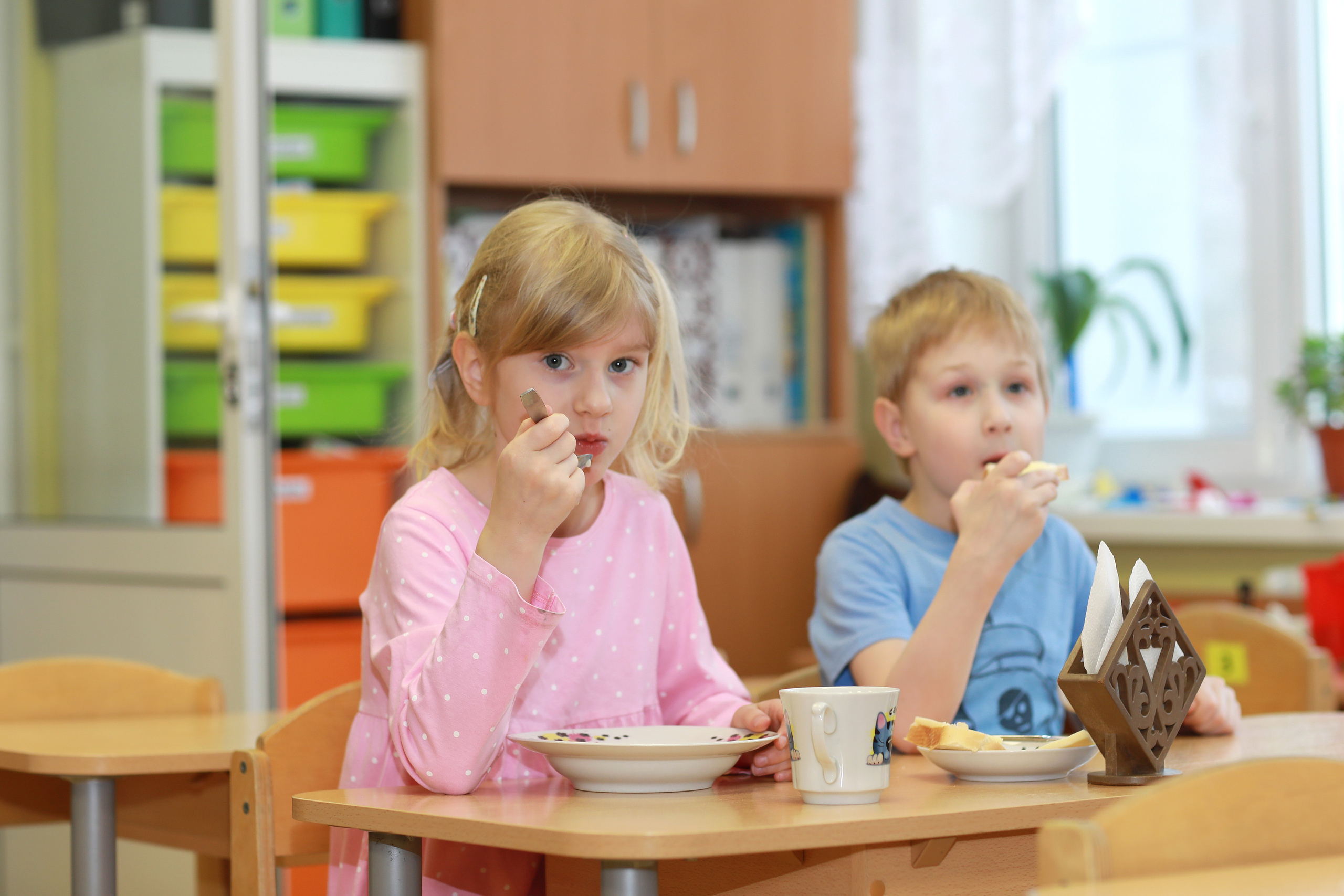 Мальчик с девочкой за едой в детском саду.