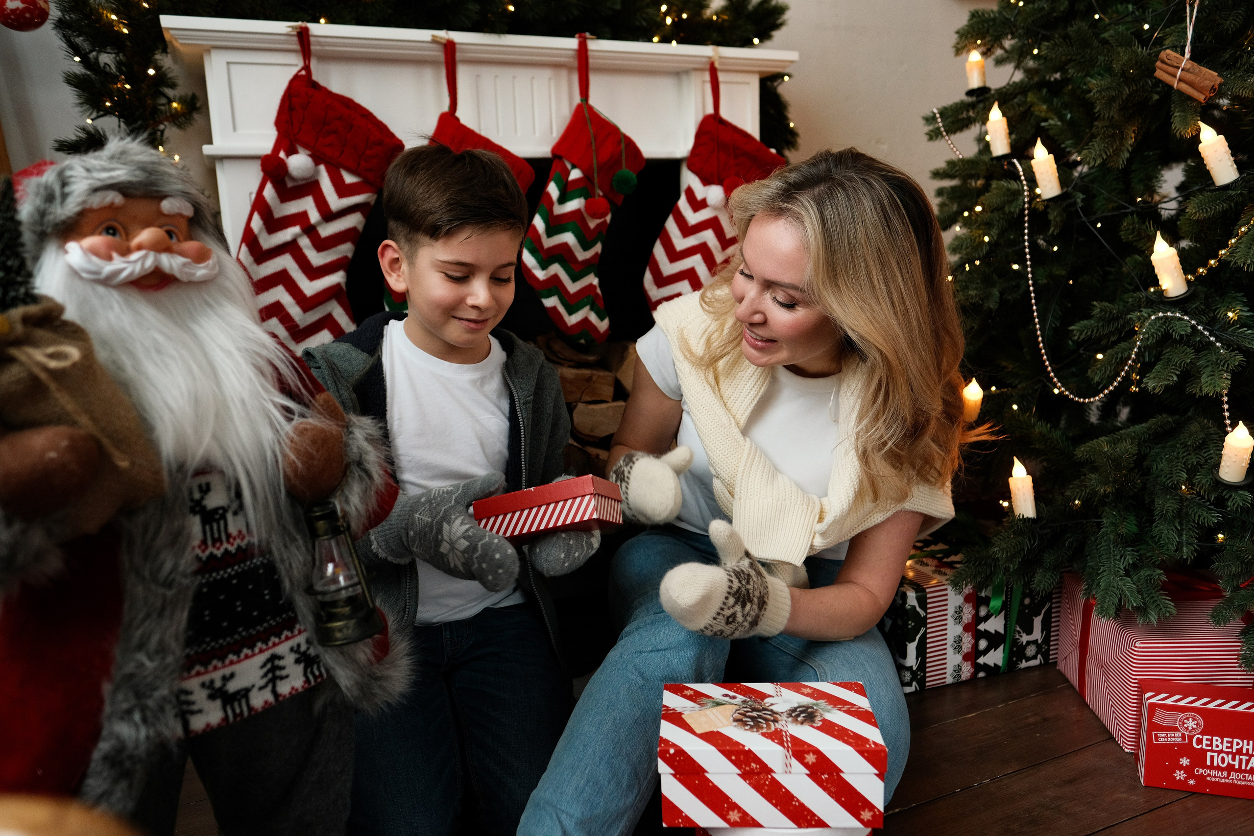 Мама и сын с подарками под новогодней елкой.