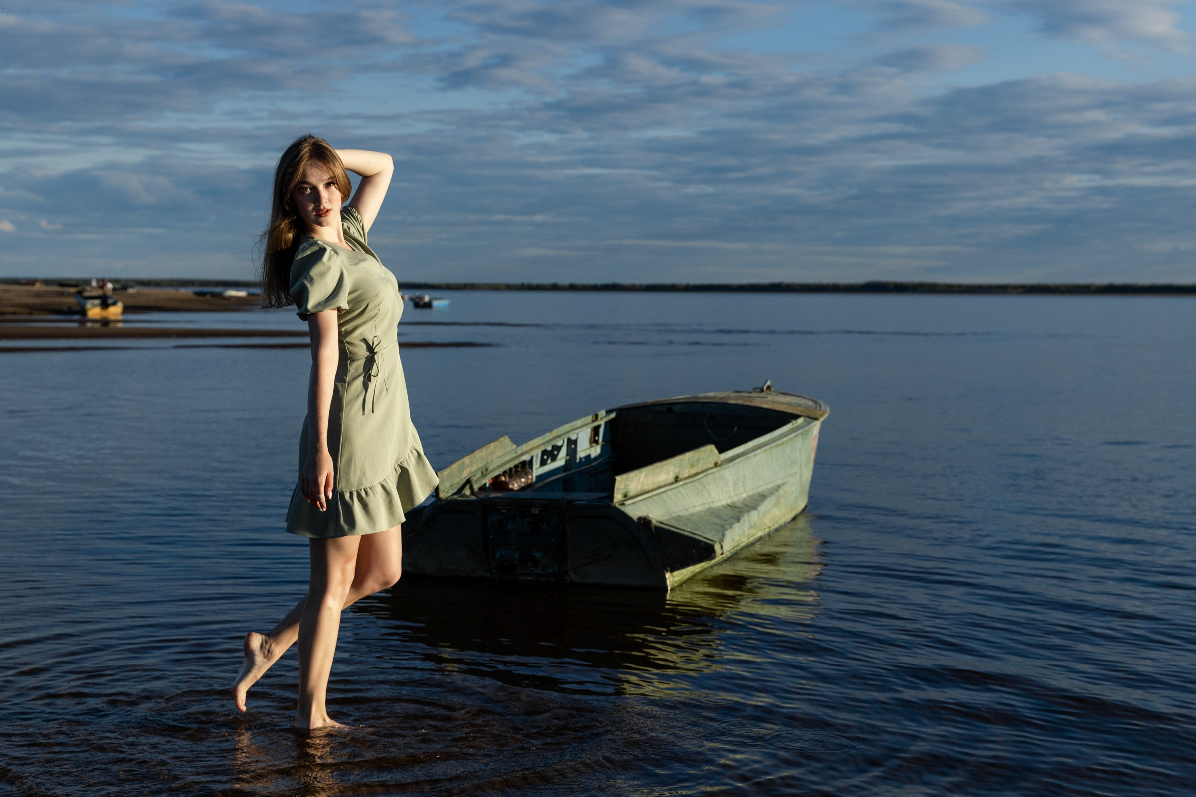 Девушка в зеленом платье на реке рядом с лодкой