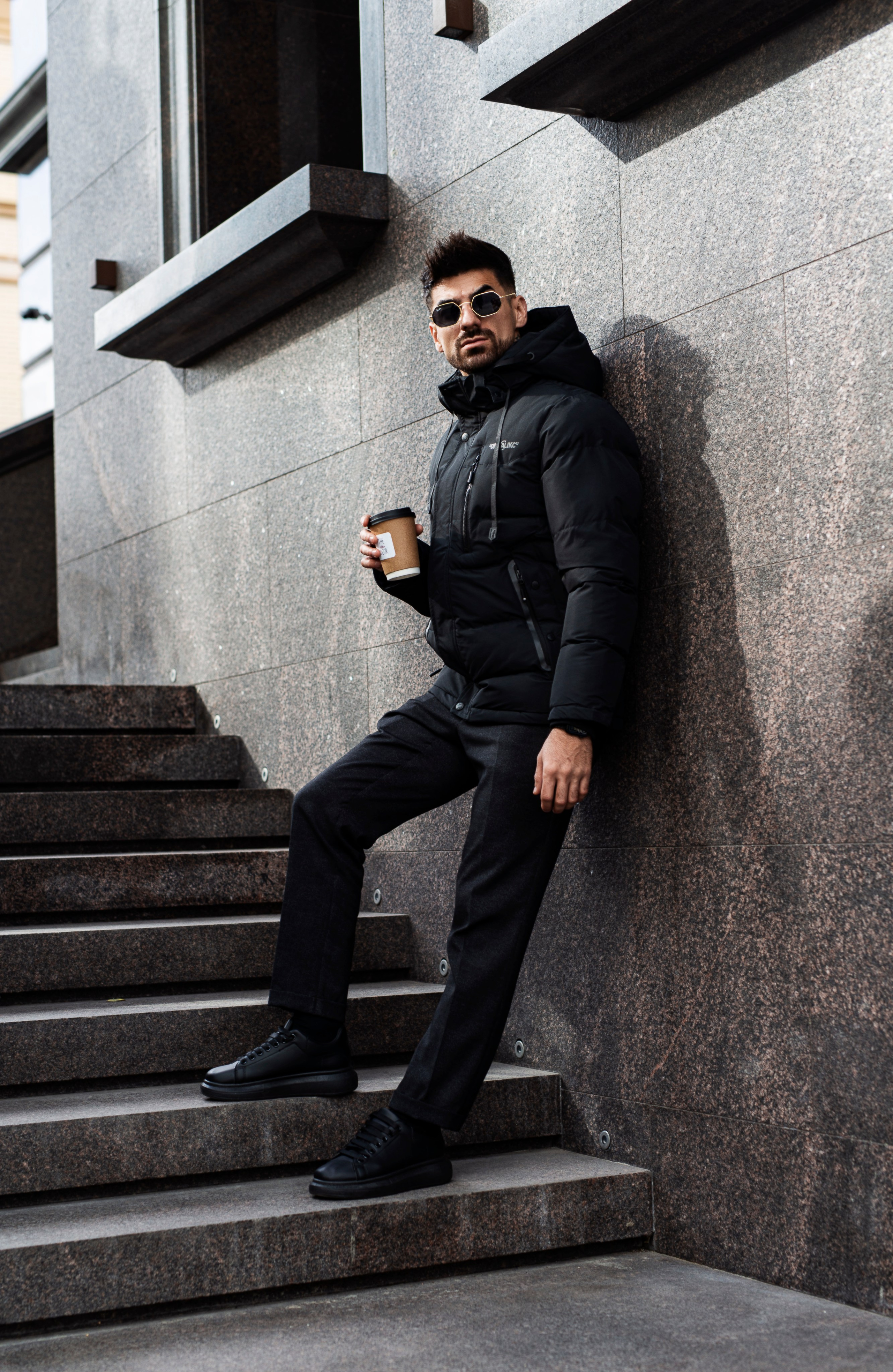 Стильный мужчина позирует на фото на фоне городской архитектуры.