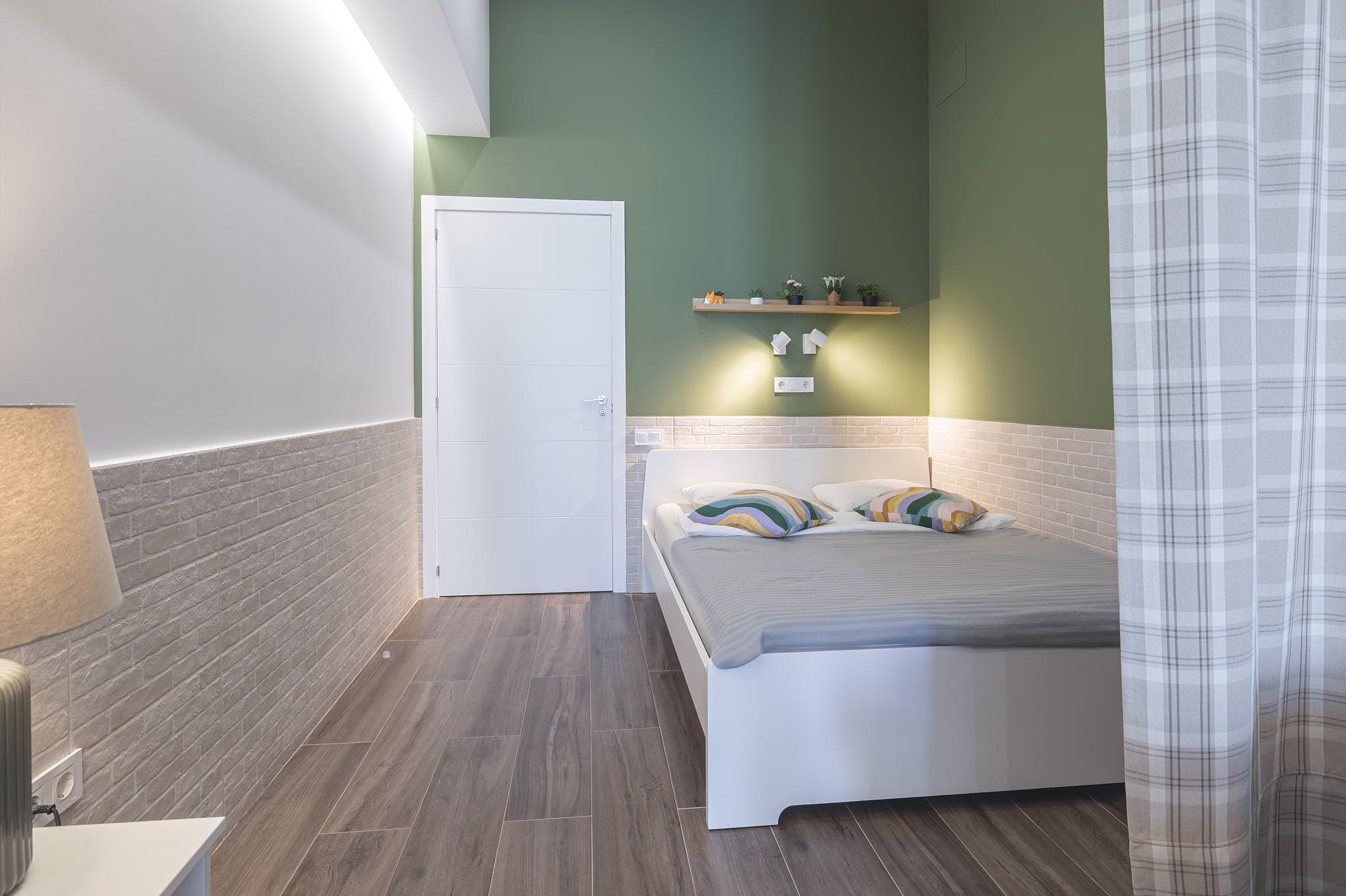 Bedroom with green wall and soft lighting in an apartment in Valencia