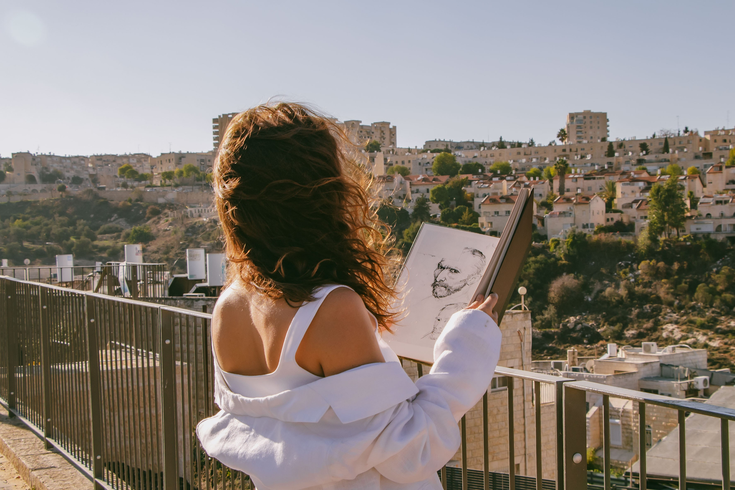 девушка повернута спиной к камере, а в руках раскрытая книга