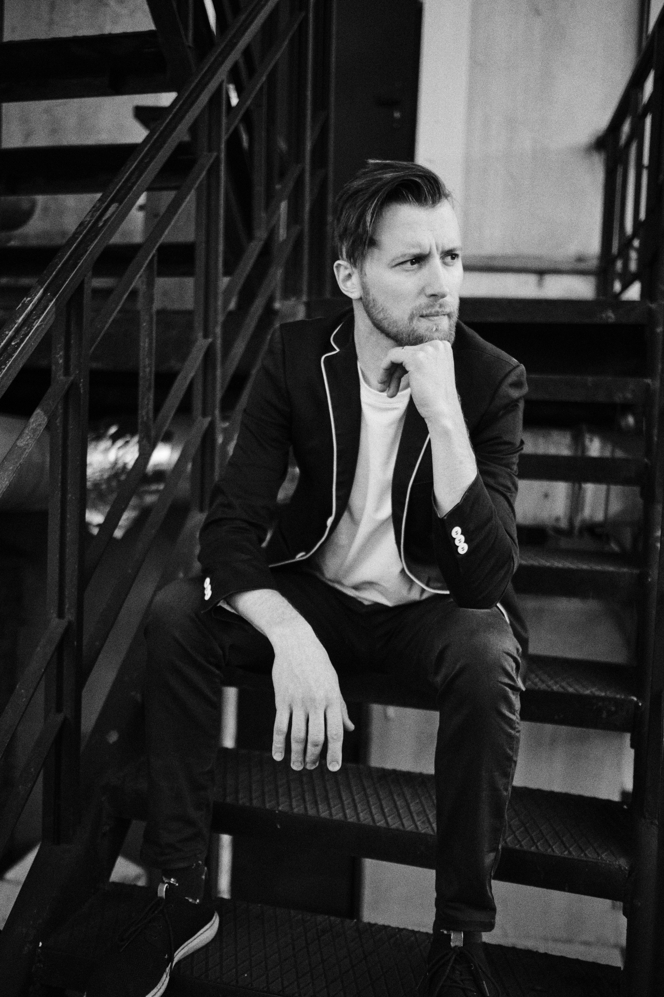 Мужчина, задумавшись, сидит на лестнице