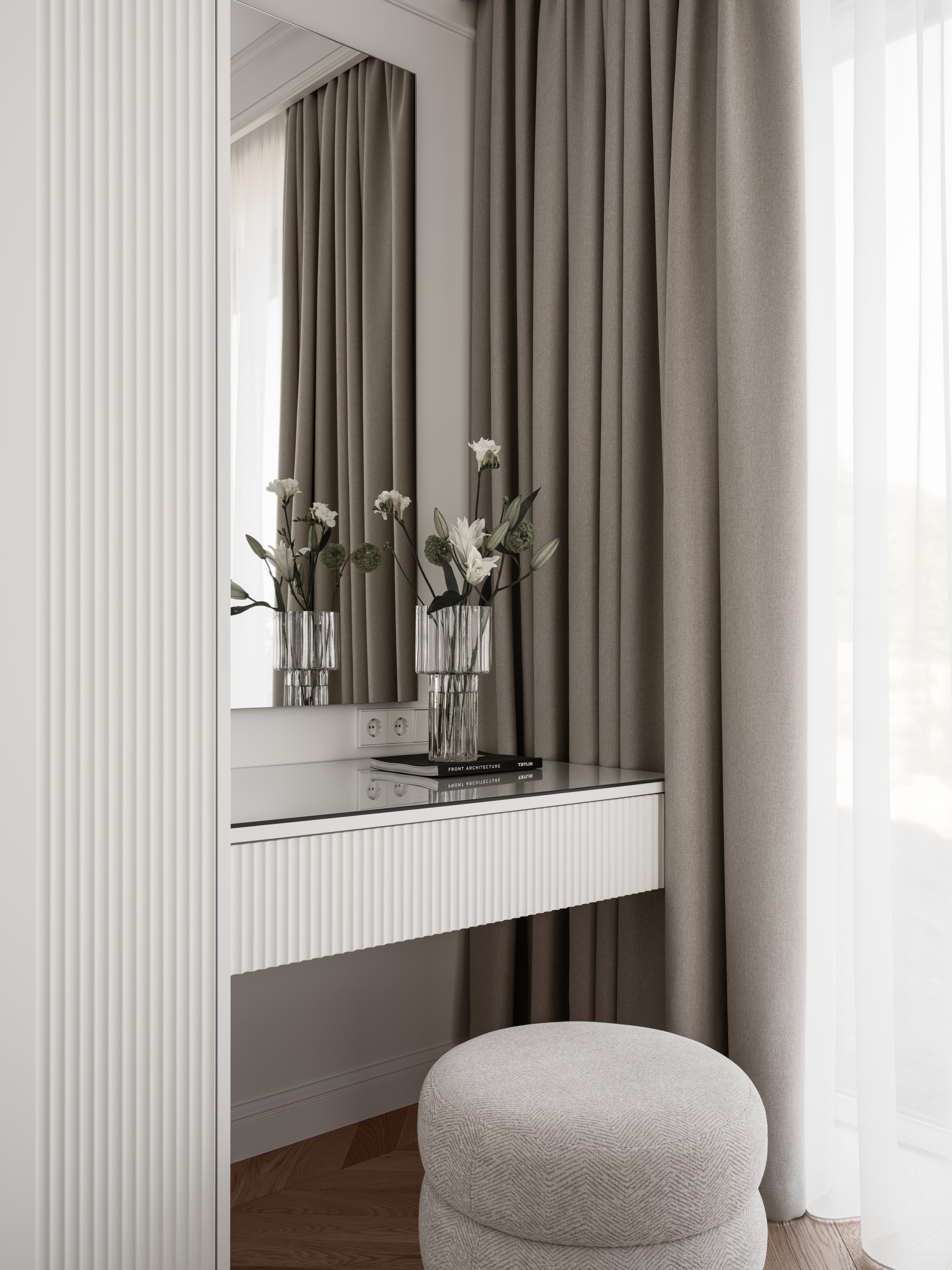 Деталь интерьера спальни с зеркалом, фактурными шторами и лаконичным туалетным столиком, оформленная дизайнером Алёной Боярской. Стилист Наталья Якушева подобрала элегантную композицию с вазой и цветами, а Сергей Денисенко отразил атмосферу спокойствия и уюта.