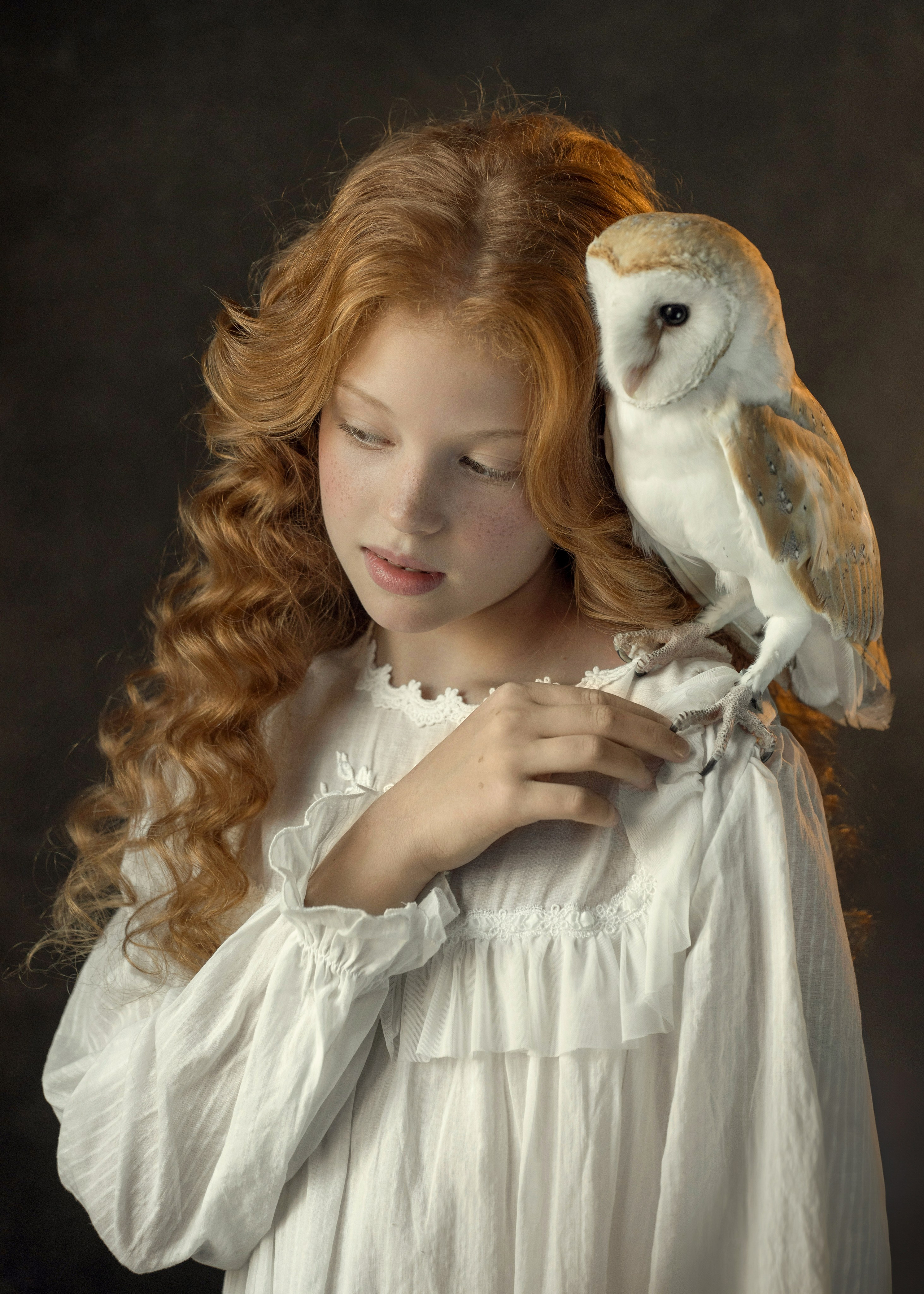 Рыжеволосая девочка с совой на плече смотрят в сторону.