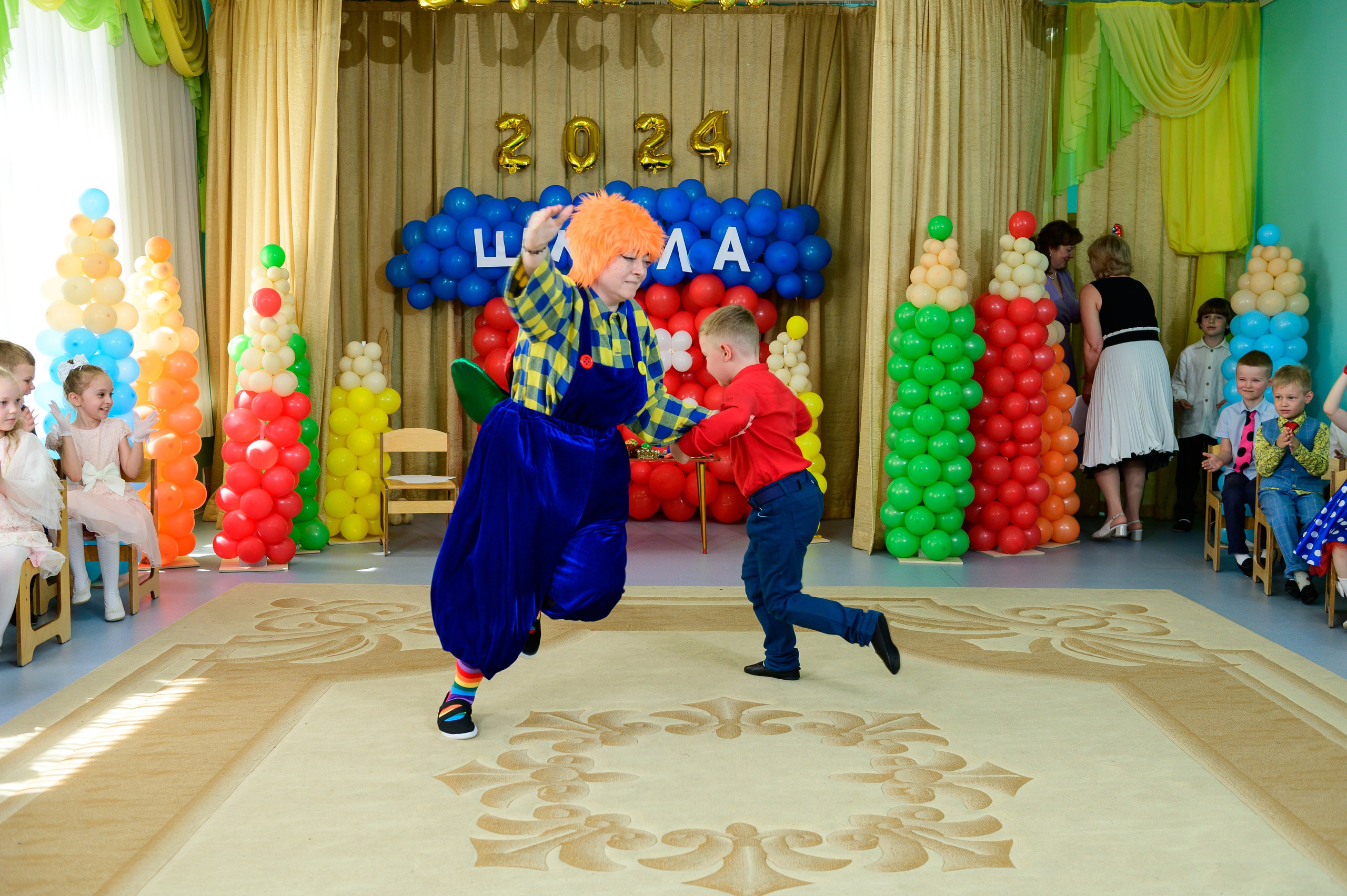 Мальчик танцует с Карлсоном на выпускном утреннике в детском саду.