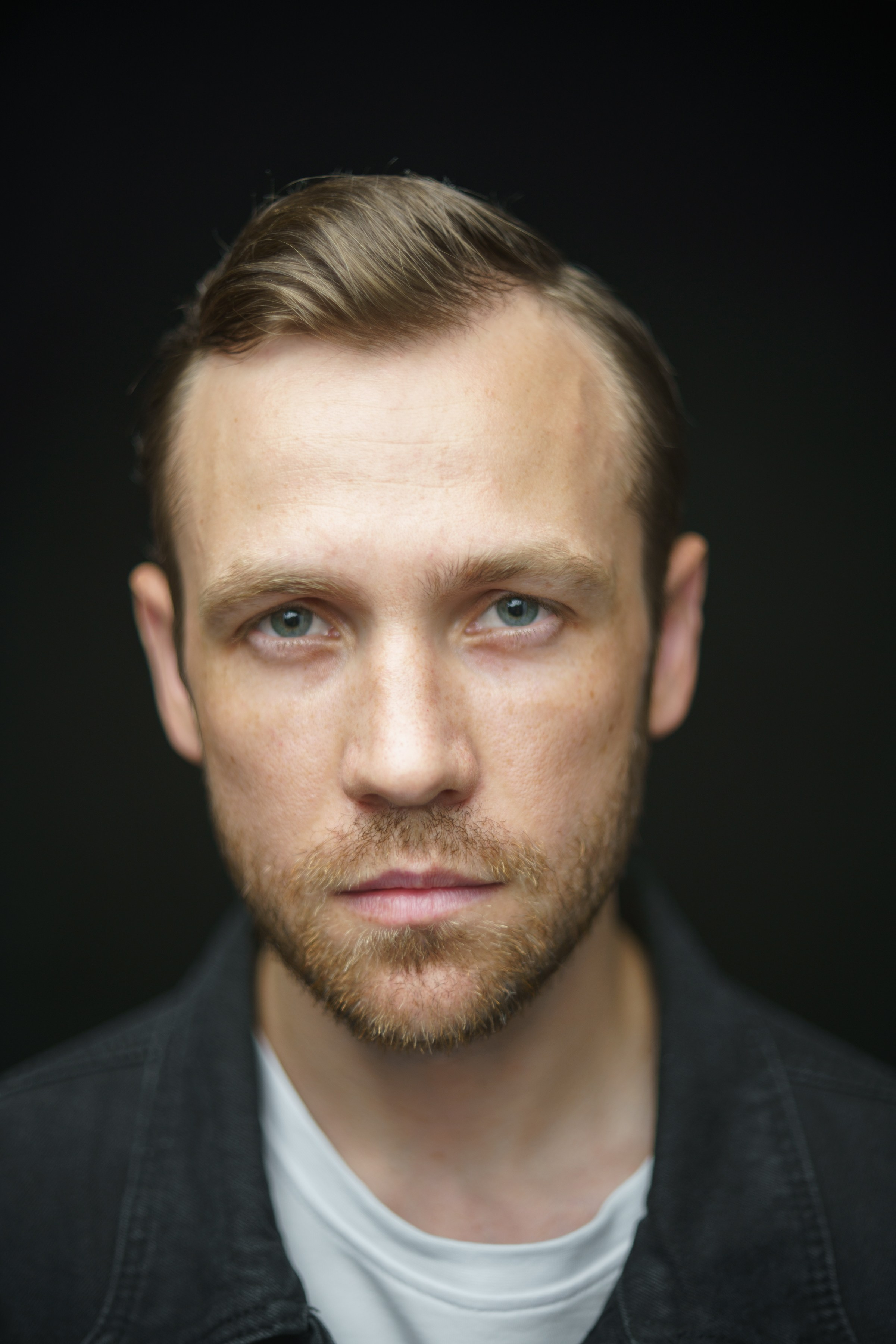 Портрет мужчины с короткой бородой в черной джинсовой куртке