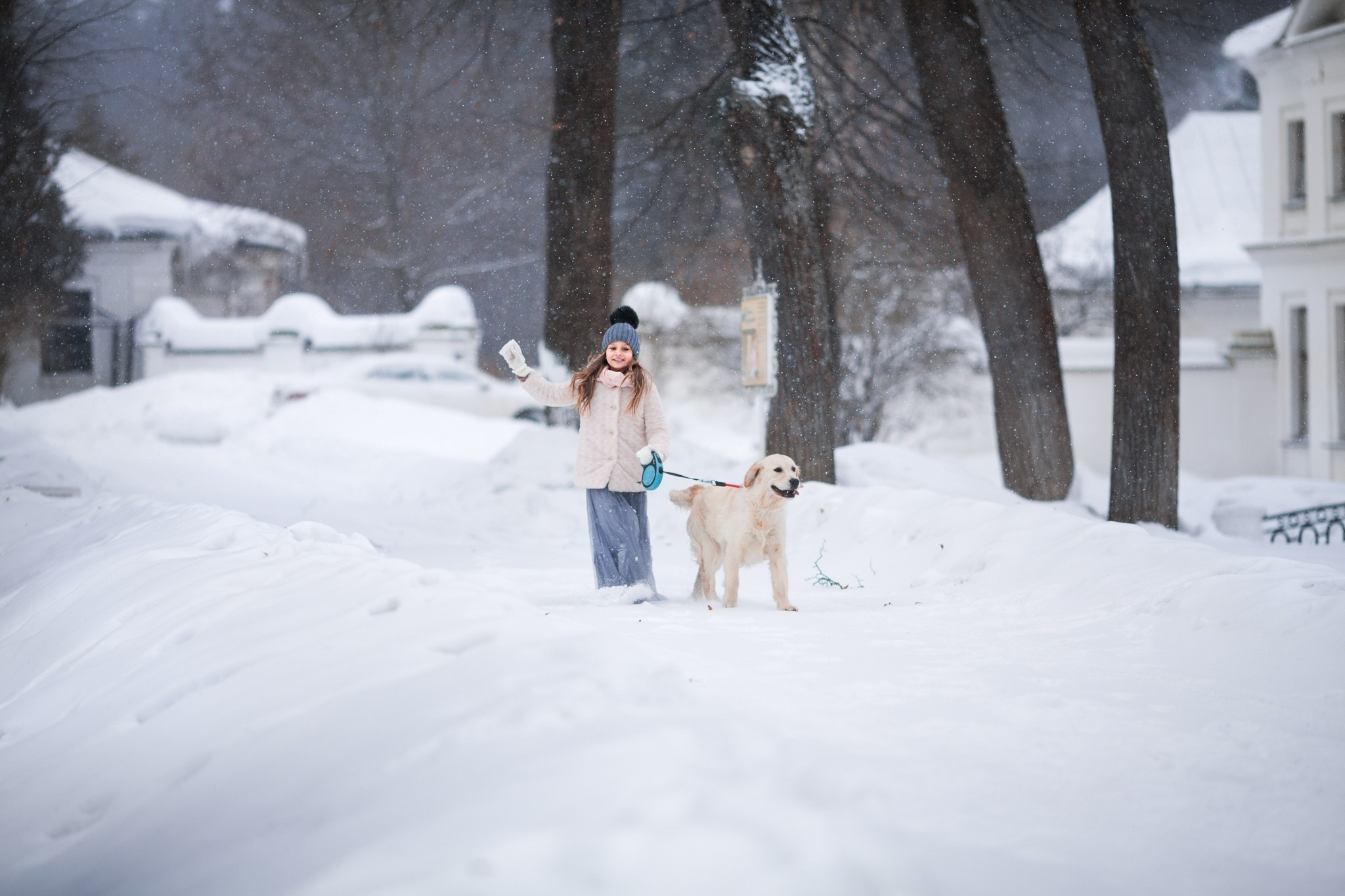 Девочка бежит по заснеженному парку с собакой
