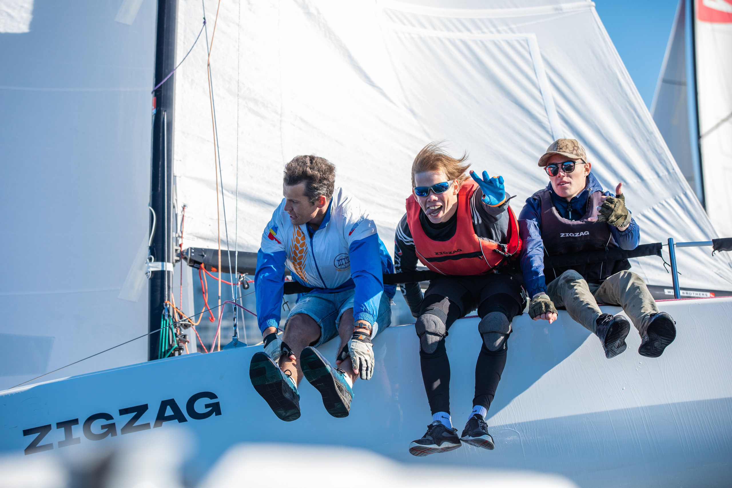 Яхтсмены откренивают лодку. Три спортсмена крупным планом.