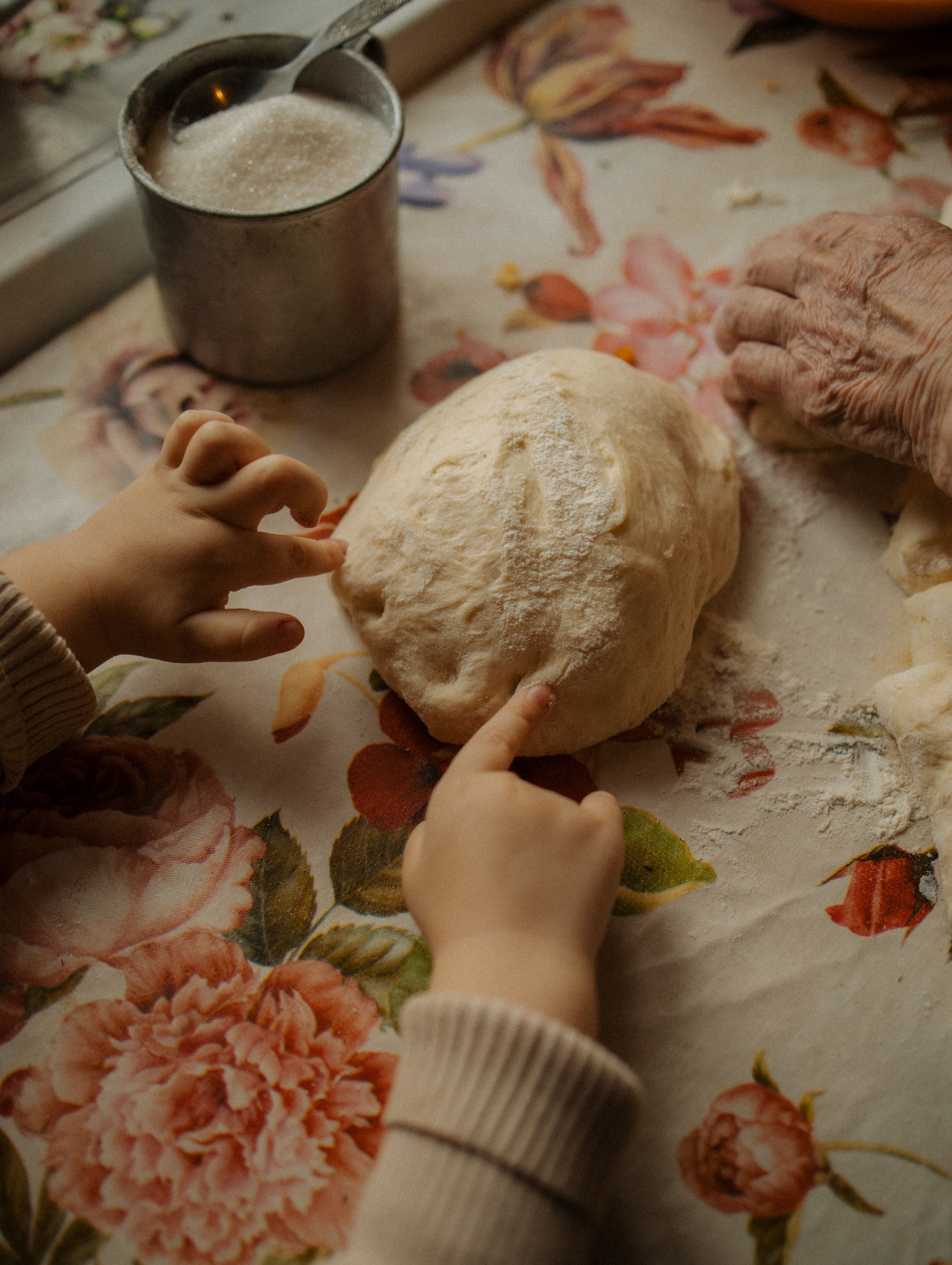 Деревенская кухня. Маленькая девочка сидит за столом на кухне и трогает тесто