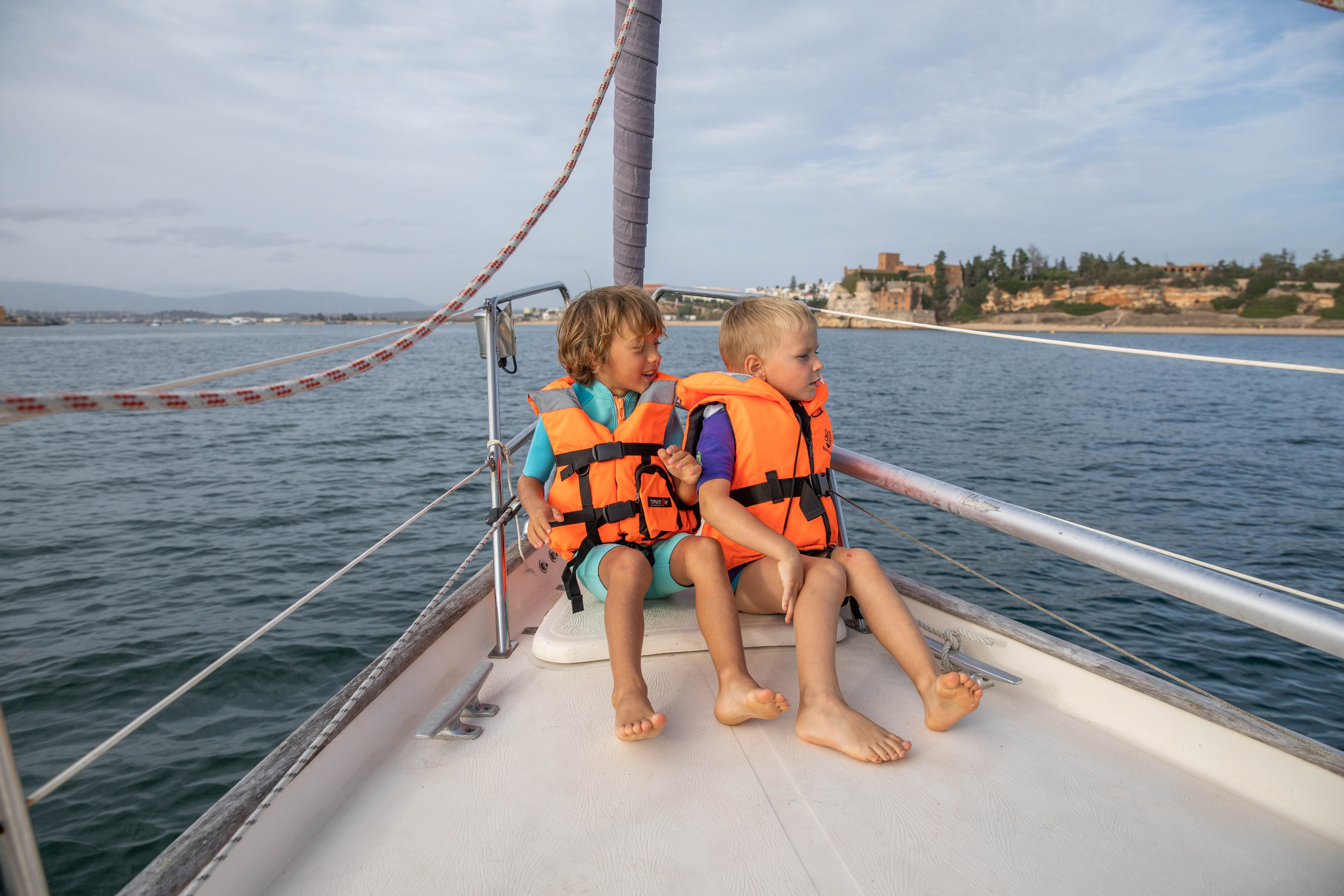 Families with children are photographed during a sailing yacht trip in the Algarve. Boys in lifejackets steer a sailing yacht and watch birds and dolphins through binoculars.