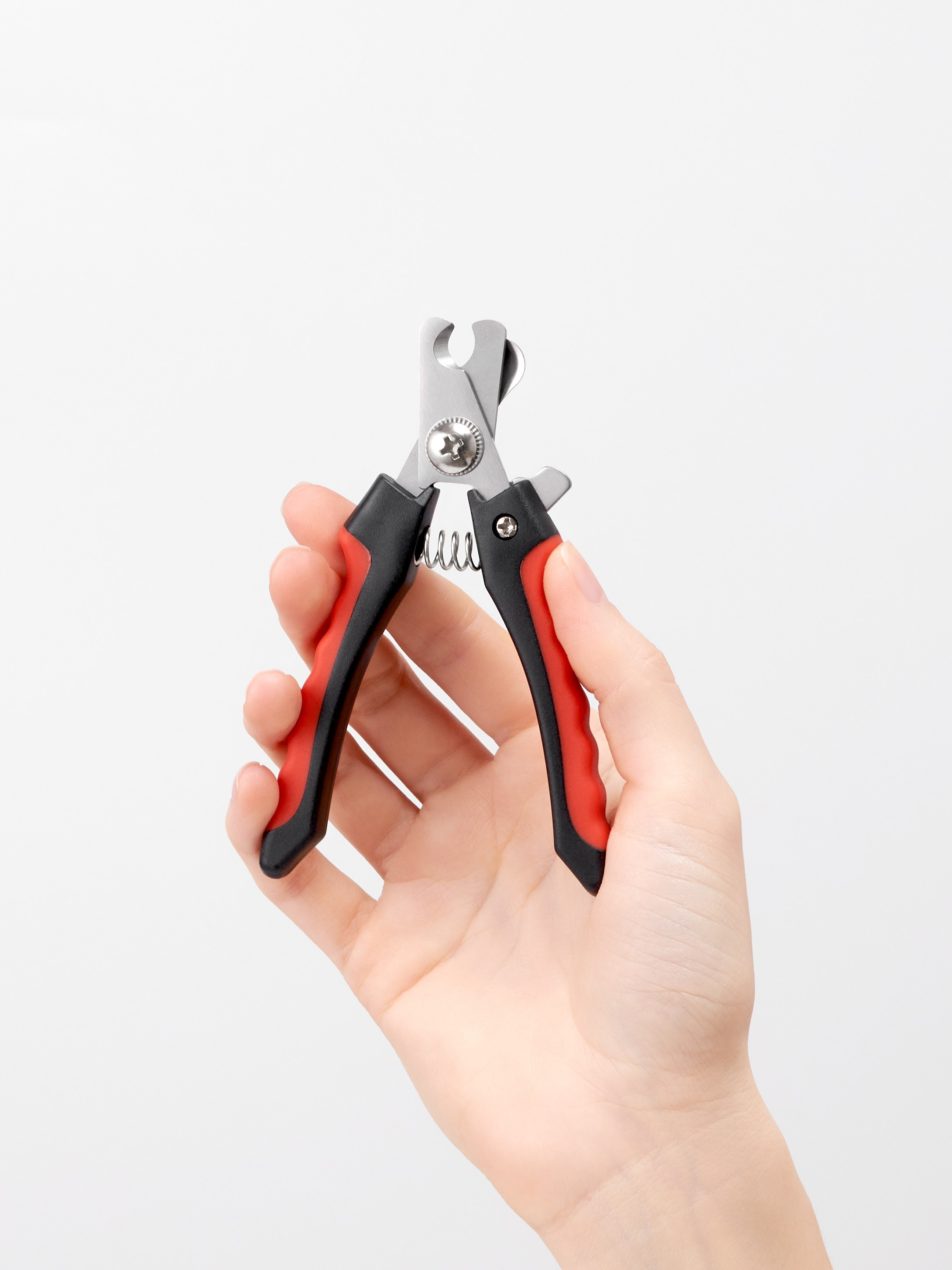 Предметная фотосъёмка красного когтереза для животных в руке модели на белом фоне