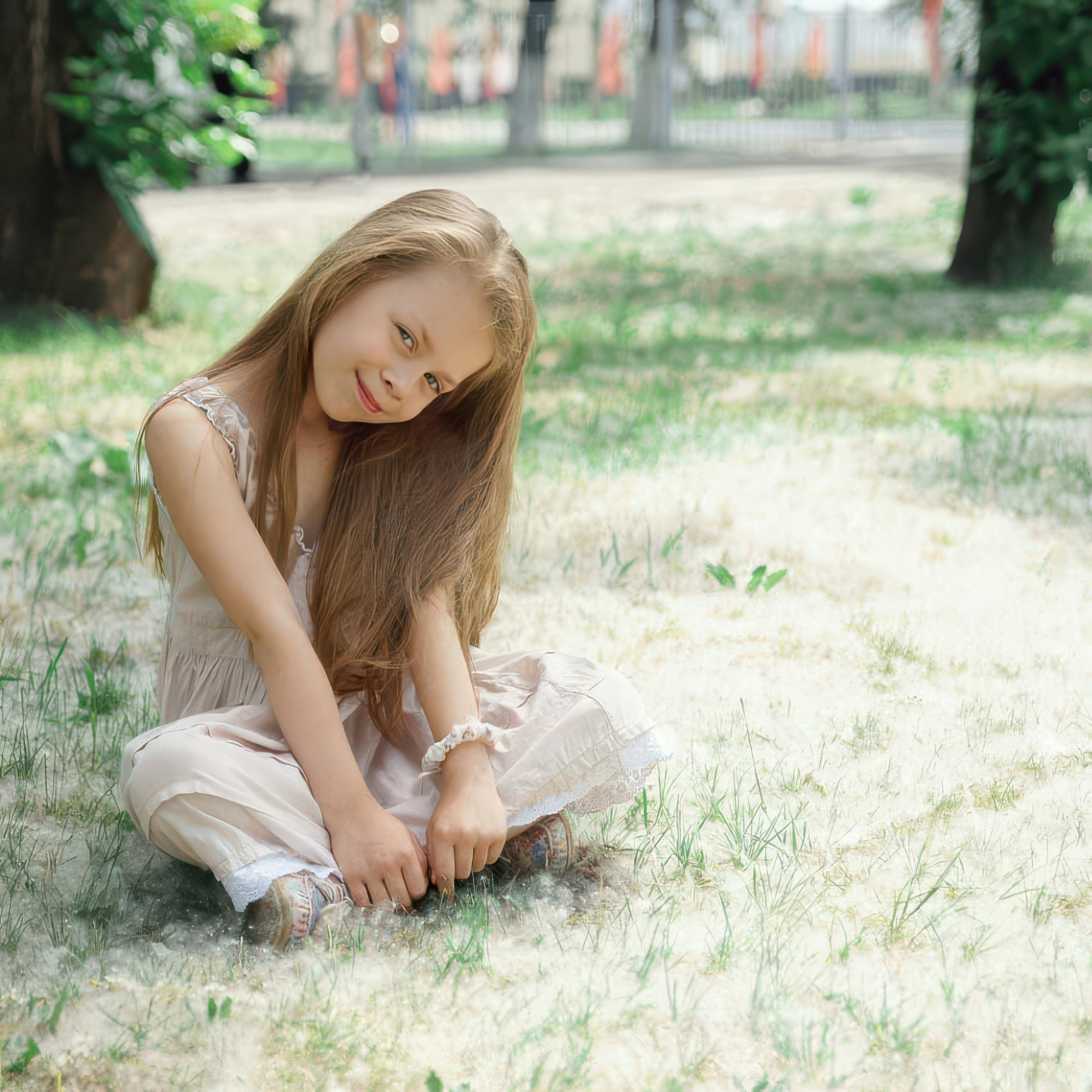 Детская фотосессия летом - девочка сидя на земле с тополиным пухом склонила голову