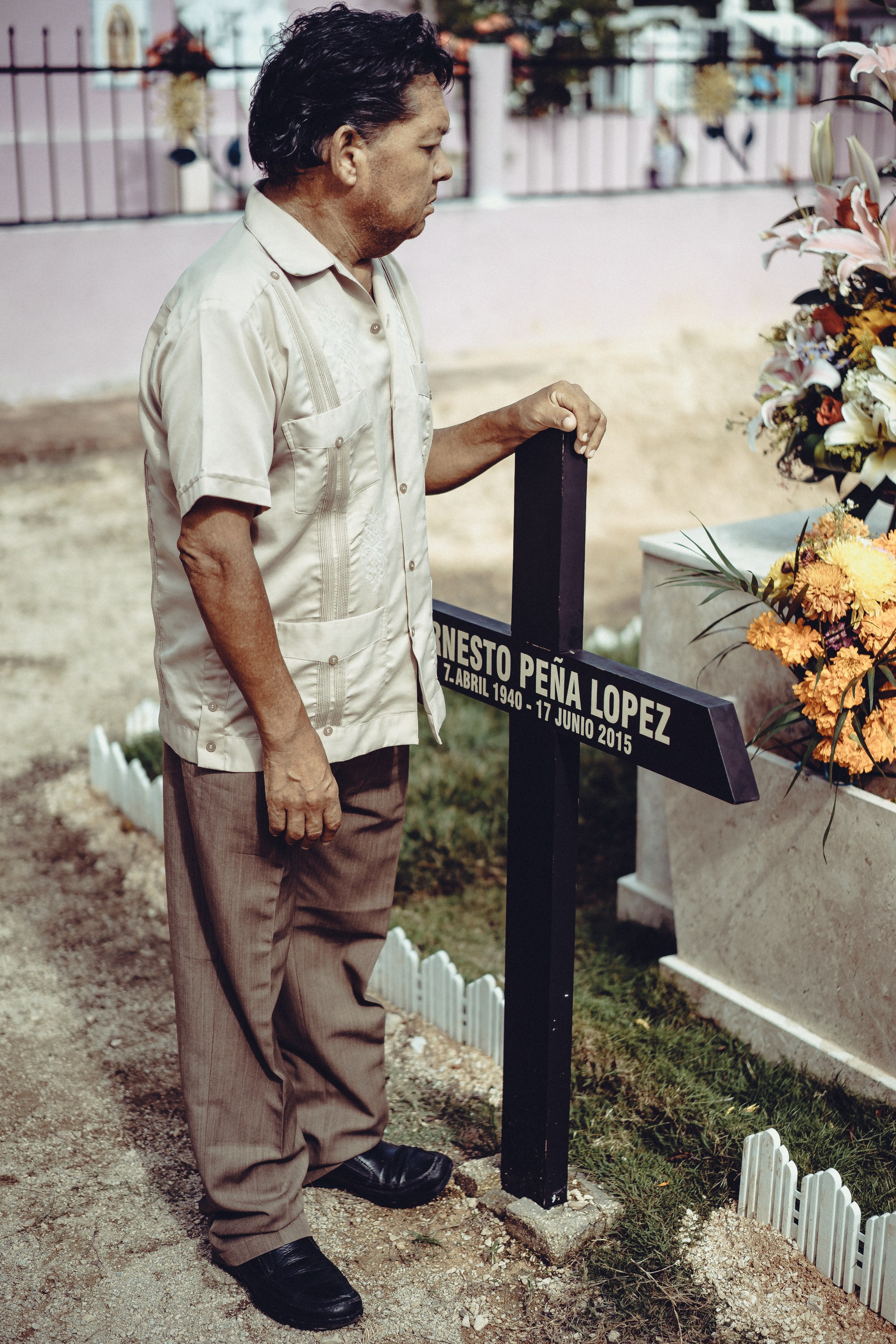 Мужчина стоит у креста на могиле родственника.