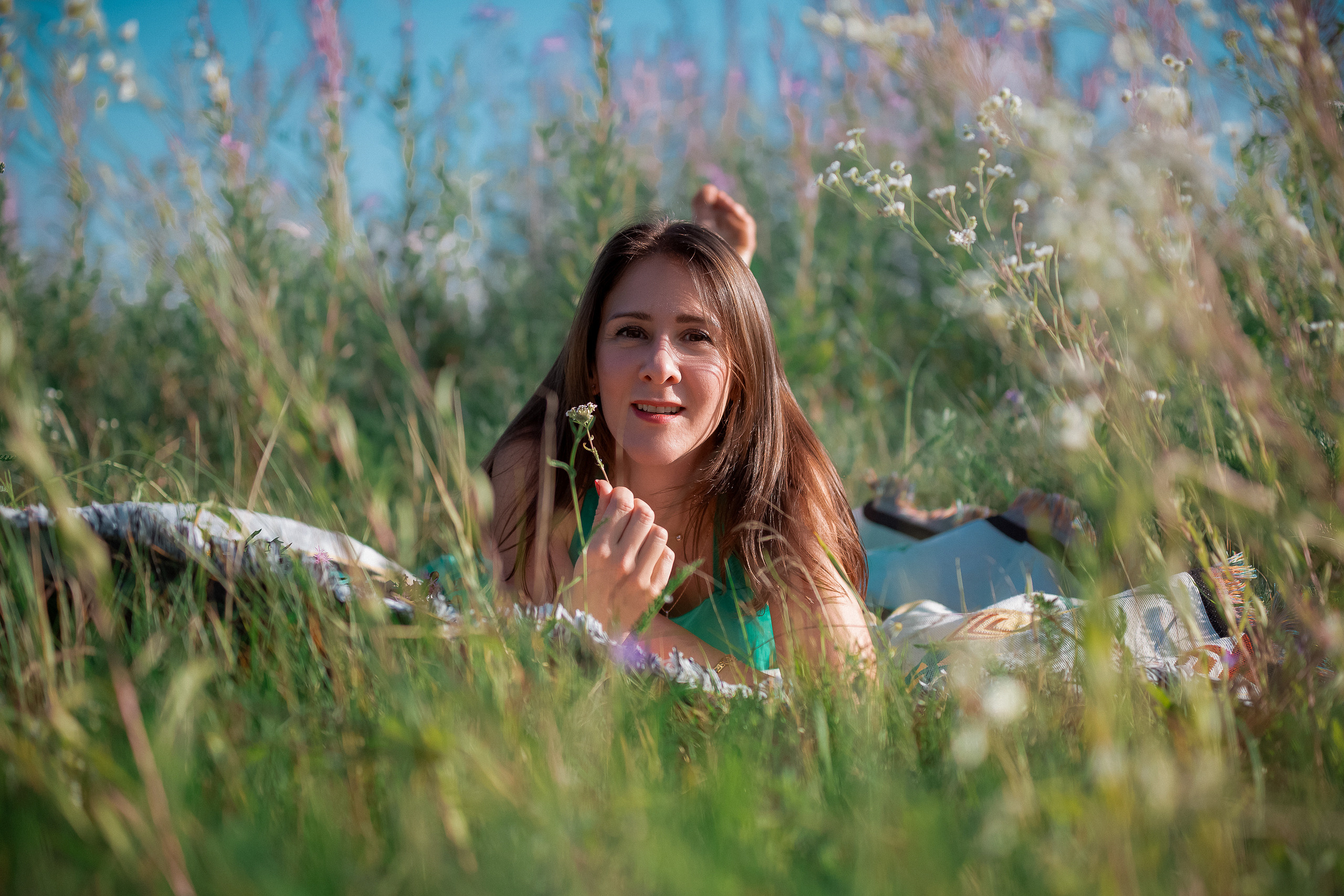 Женщина лежит на животе в поле на пледе