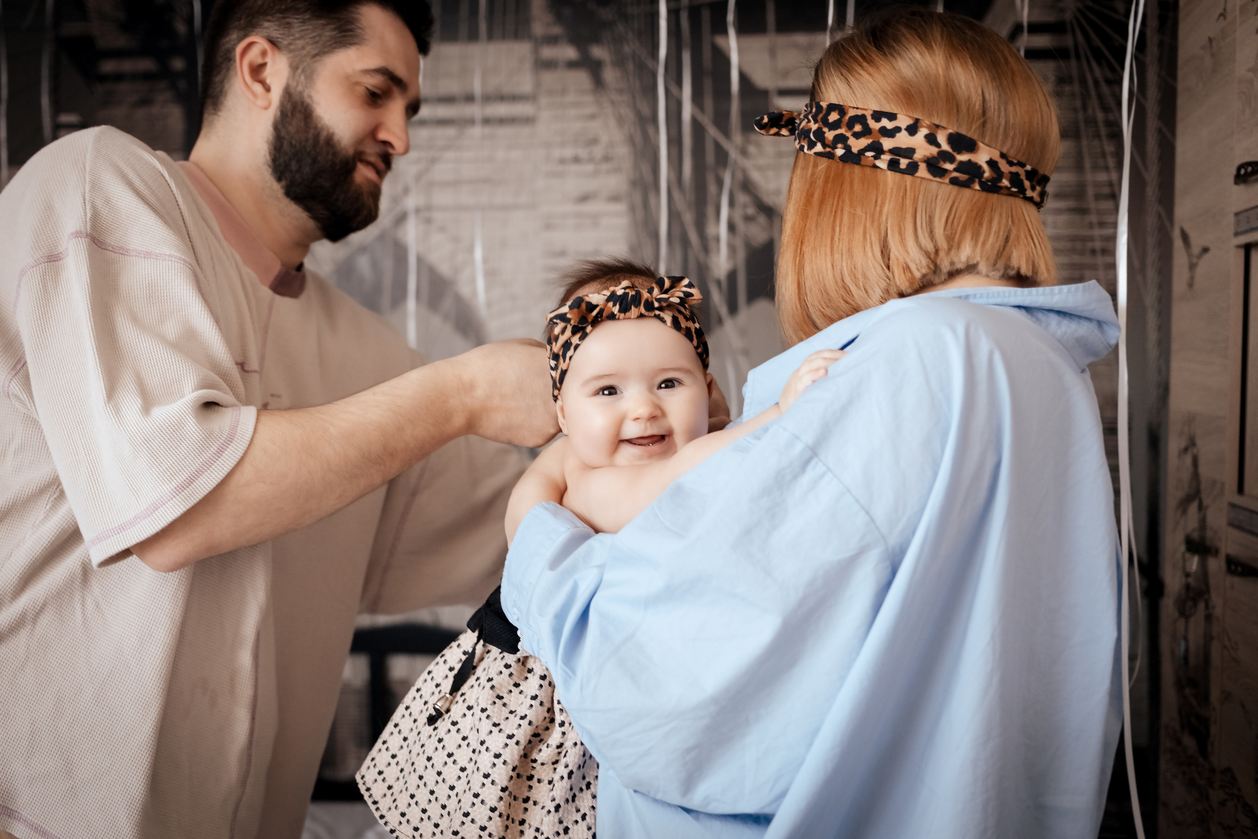 Мама и папа одевают маленькой дочке платье