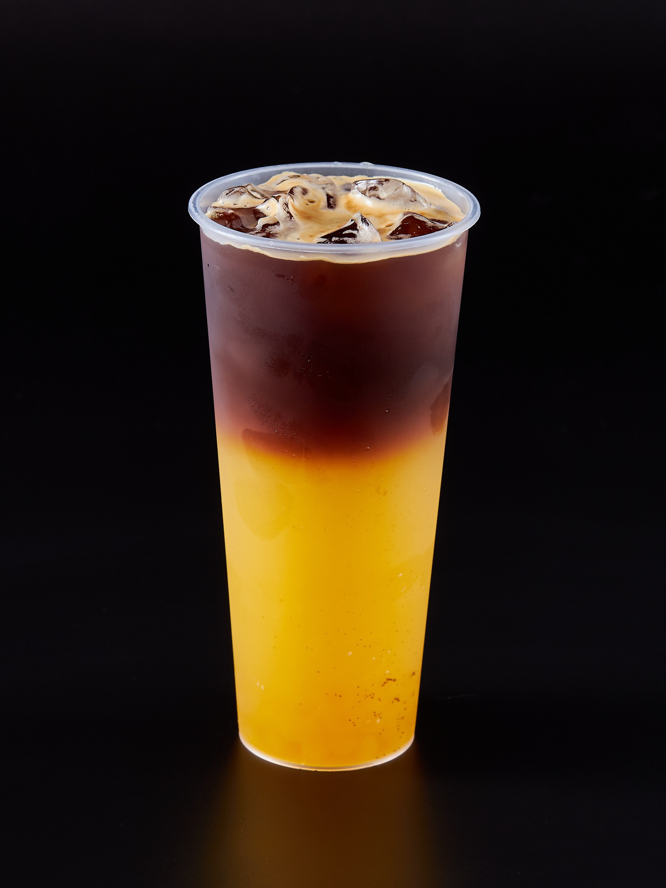 Коктейль в пластиковом стакане желтого цвета на черном фоне