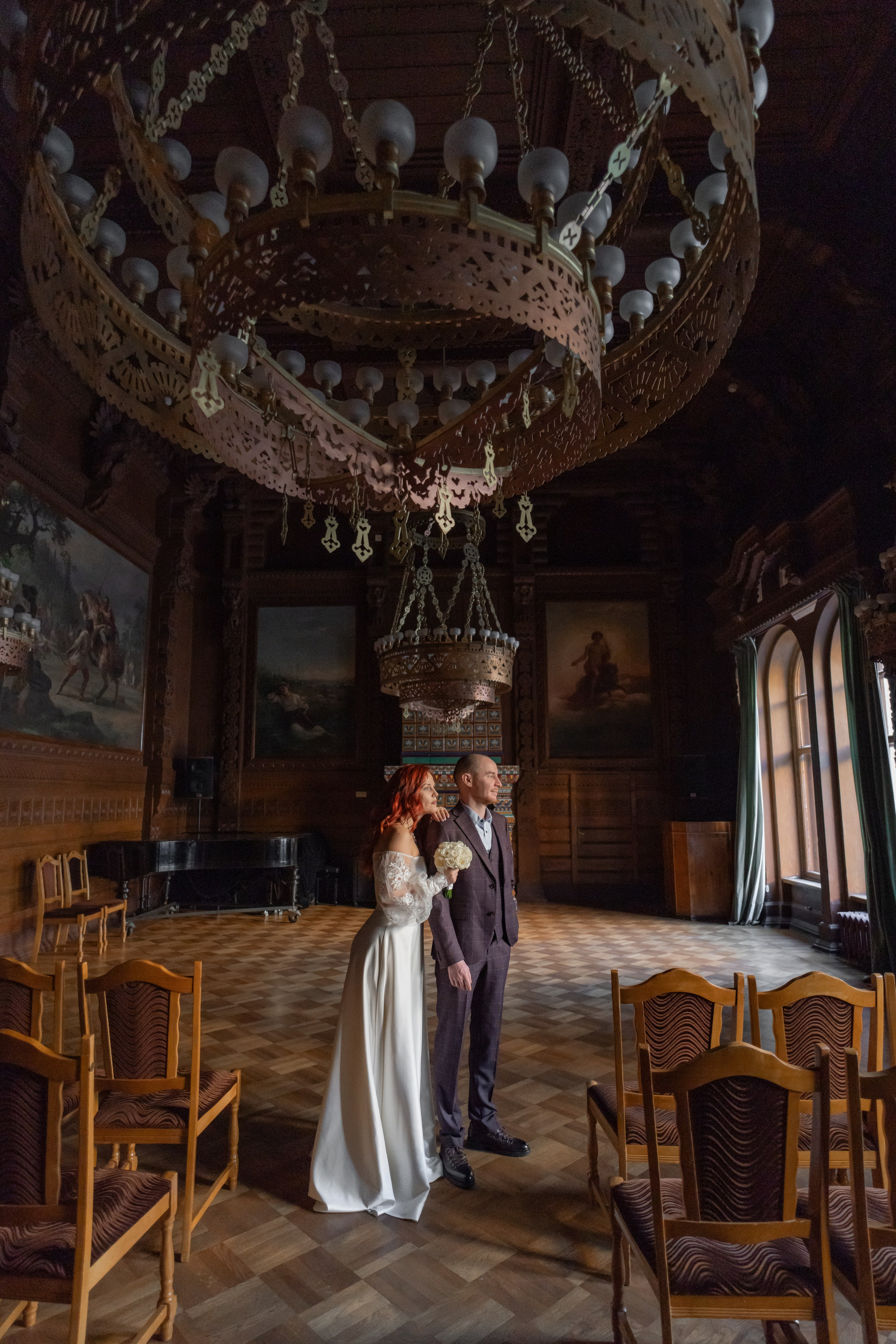 Жених и невеста  обнимаются в дубовом зале во Дворце Великого Князя Владимира на свадебной фотосессии