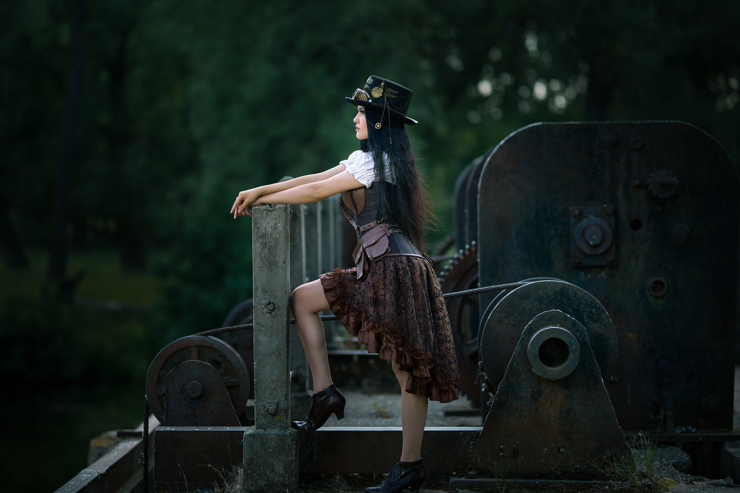 Девушка в костюме в стиле Стимпанк стоит рядом с механизмом в шляпе