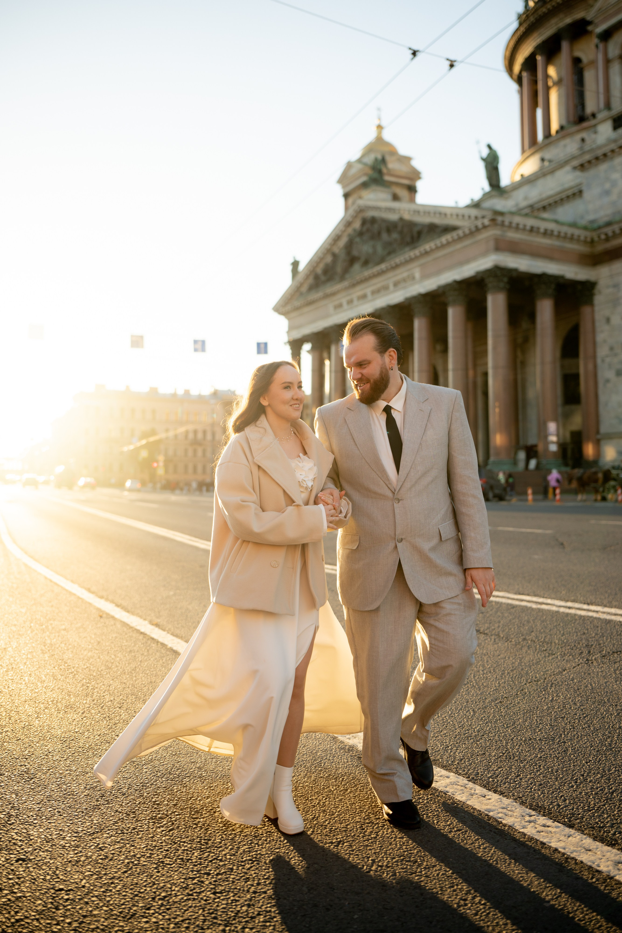Свадебная фотосессия у Исаакиевского собора на закате жених и невеста идут в лучах солнца