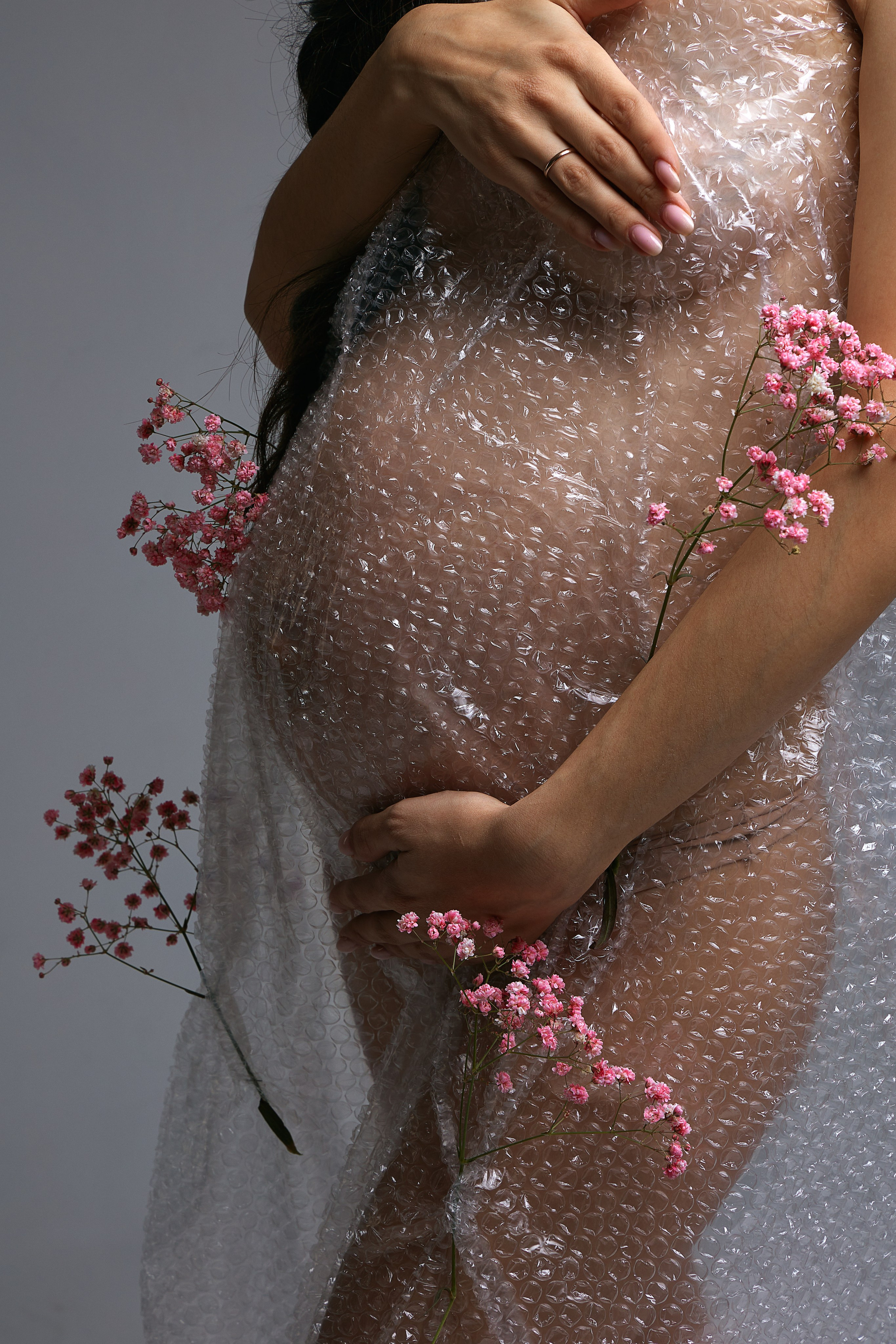 Беременная девушка в фотостудии в пленке и цветах