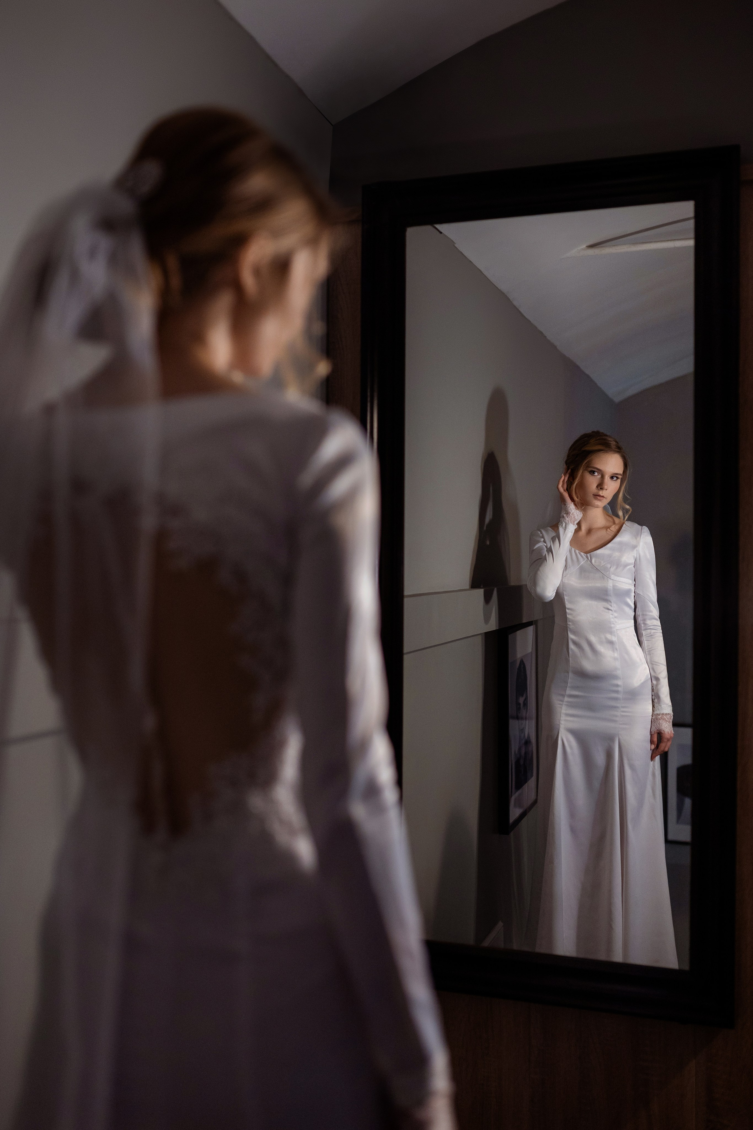 Невеста стоит перед зеркалом, смотрит на свое отображение.