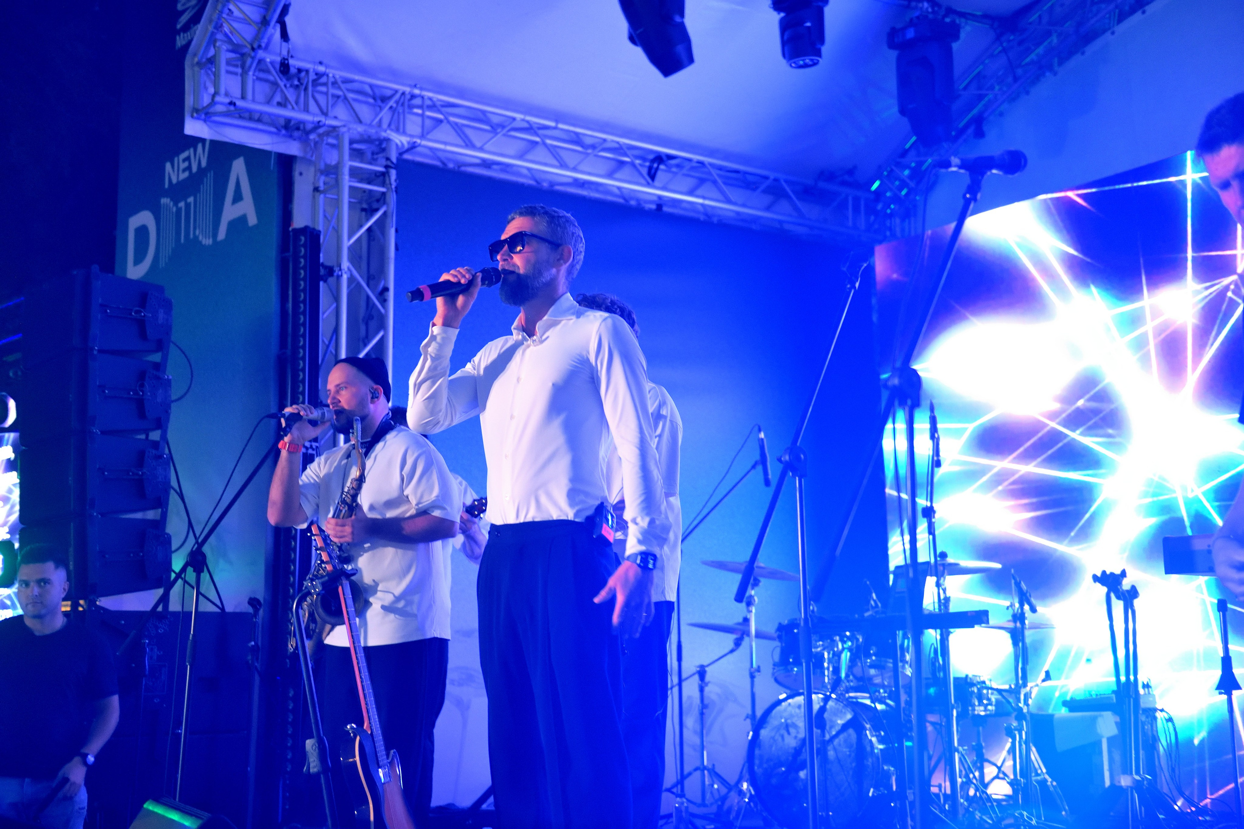 "Общий план сцены, группа выступает в синем цвете на сцене".