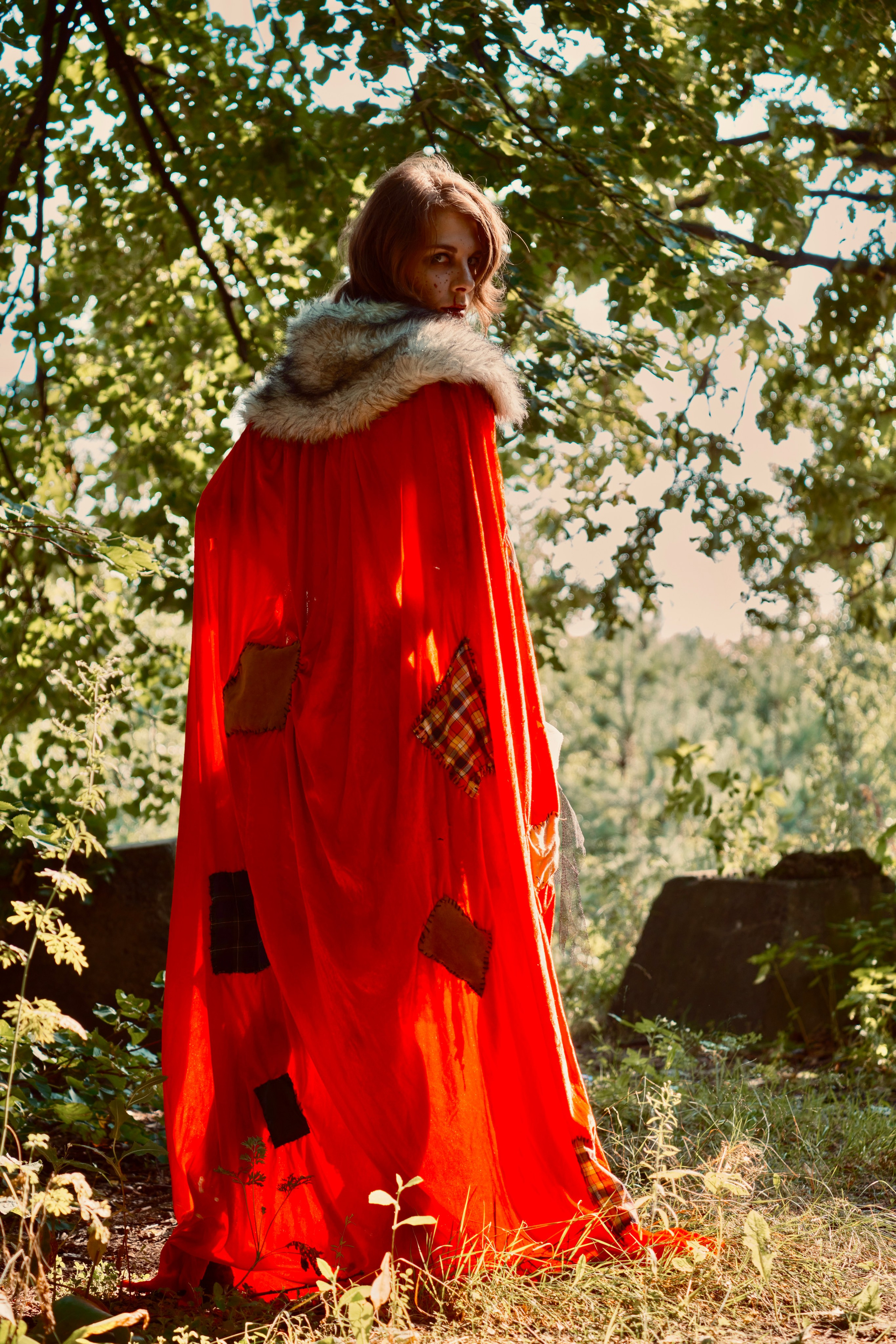 Девушка в красном плаще с корзиночкой гуляет в лесу