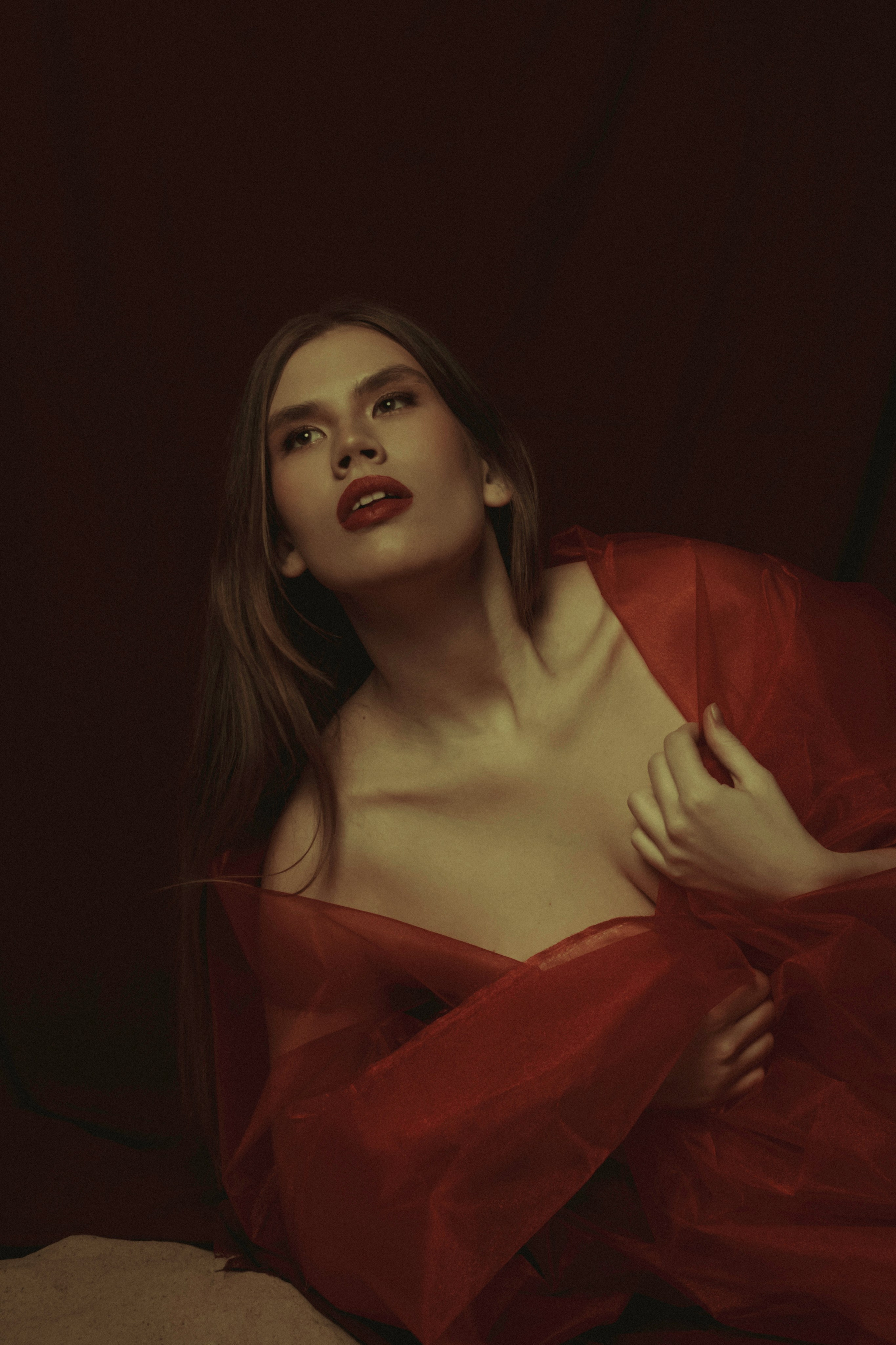 фото в стиле классической картины в стиле Рубенса, девушка лежа на песке в красной ткани смотрит вверх 