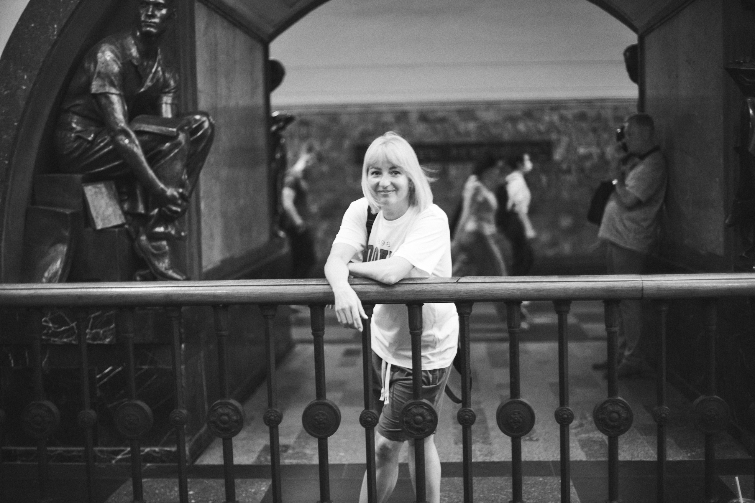 Девушка стоит в метро, облокотившись о перила