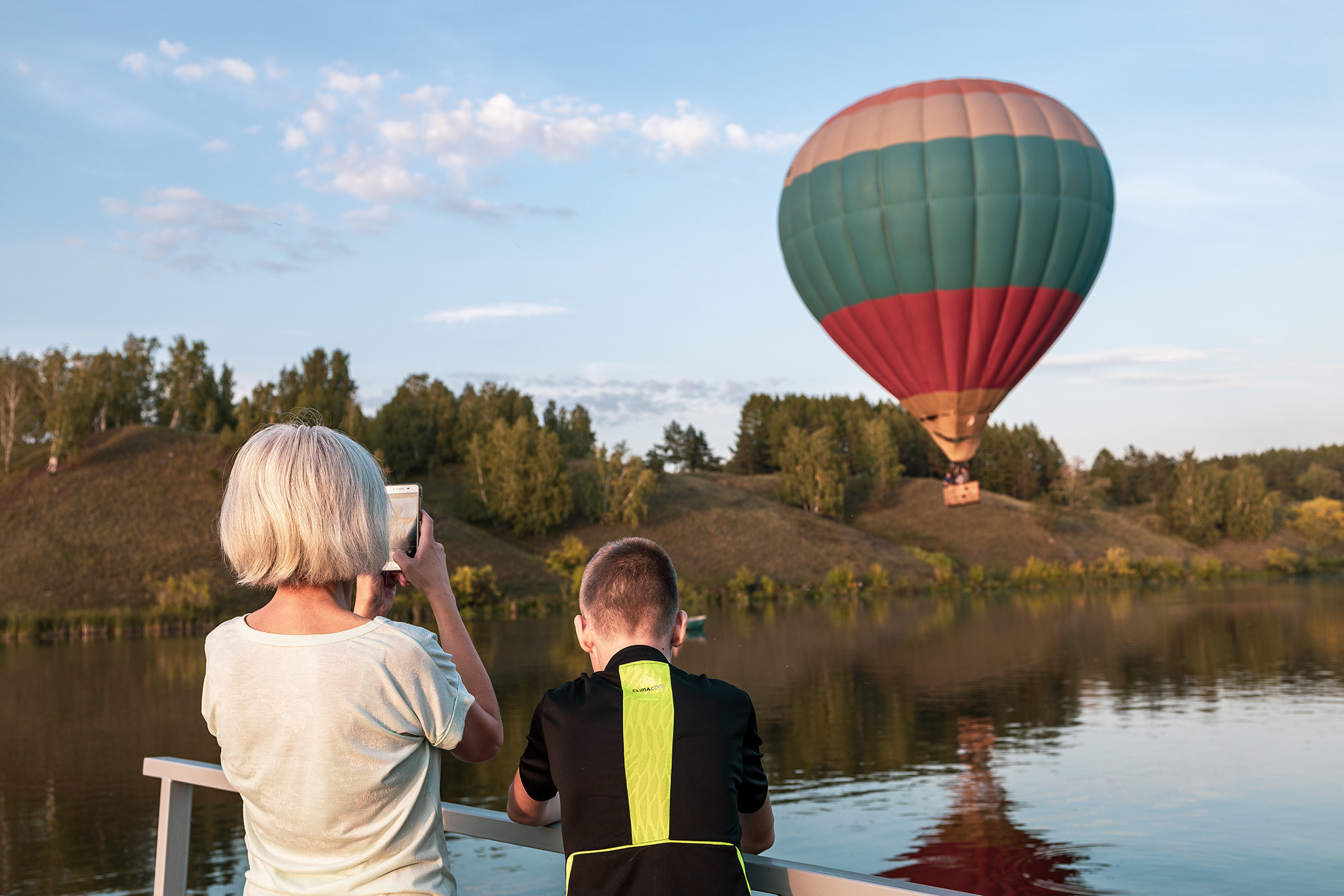 Люди фотографируют воздушный шар на реке