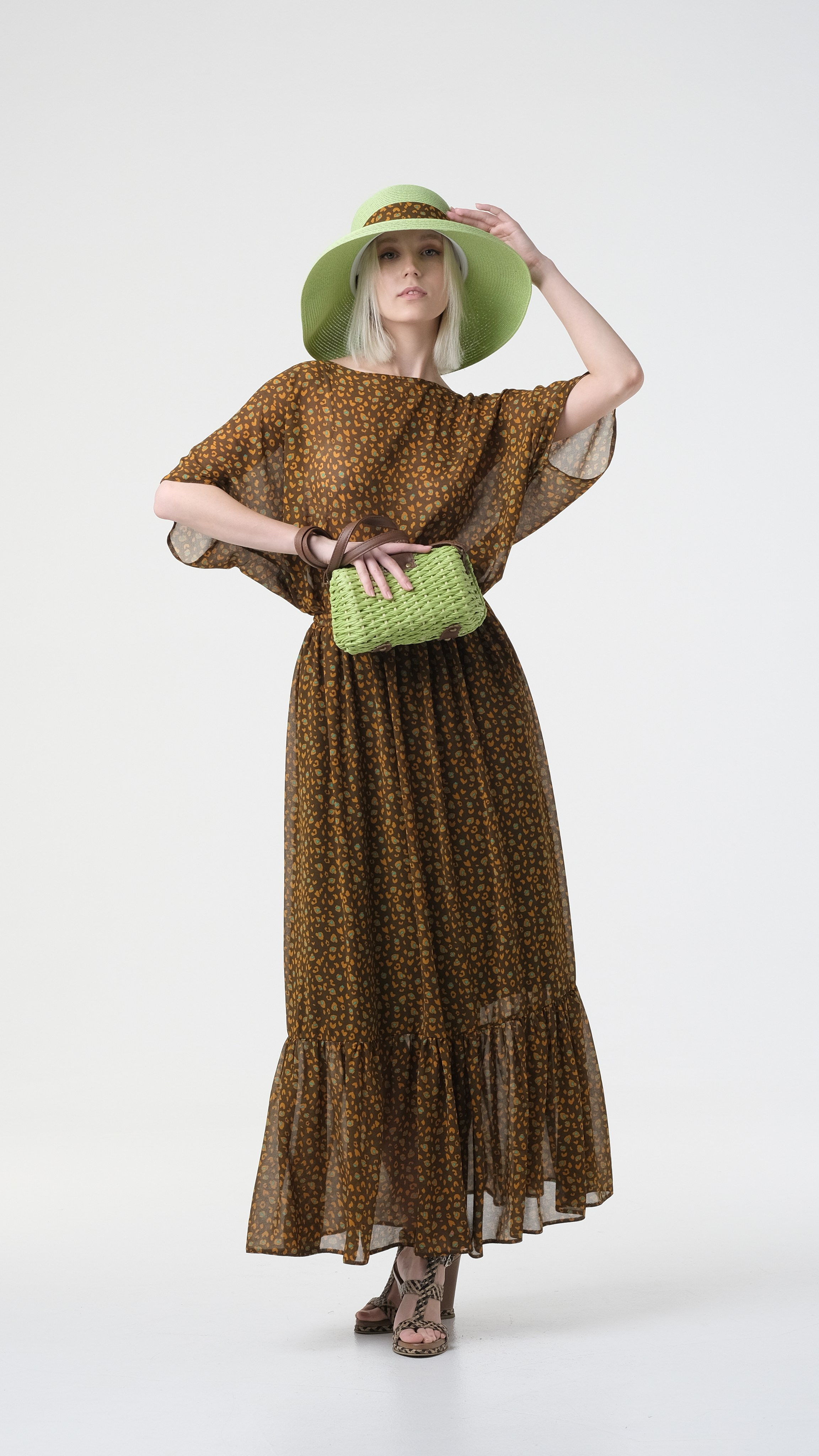 Съёмка для модельного портфолио на циклораме, красивое позирование. Модель в зеленой шляпе и с зелёной сумочкой.