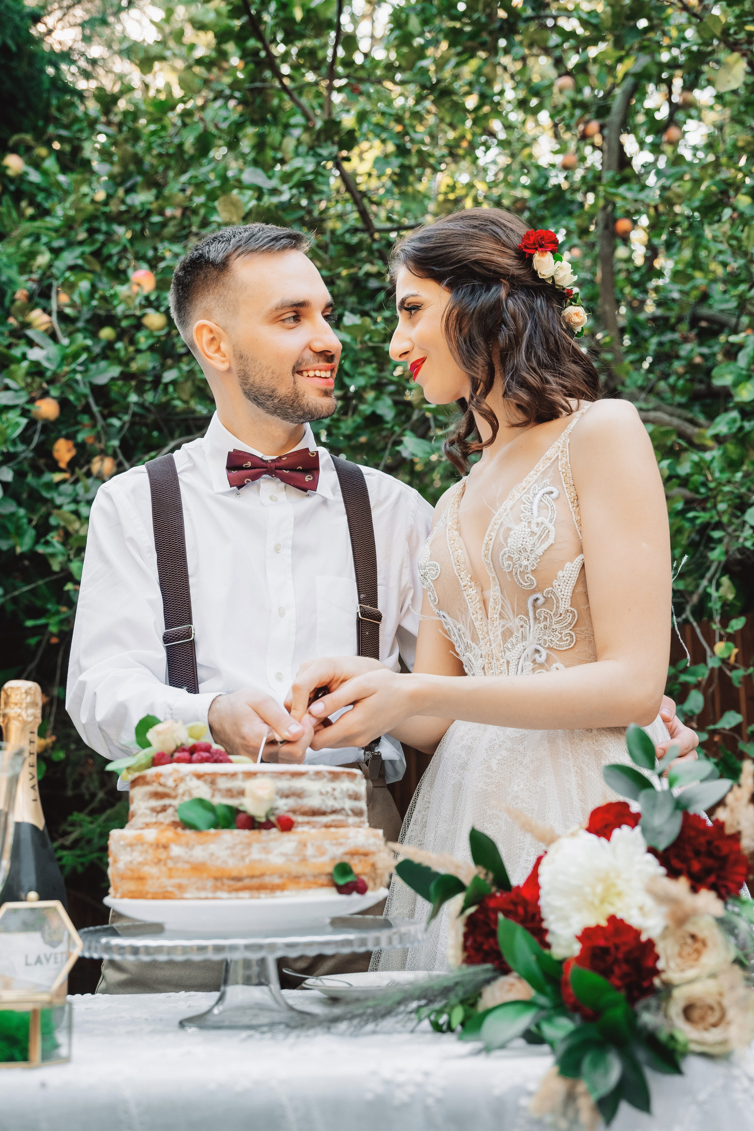 Летний день, закатное солнце, молодожены разрезают красивый свадебный торт