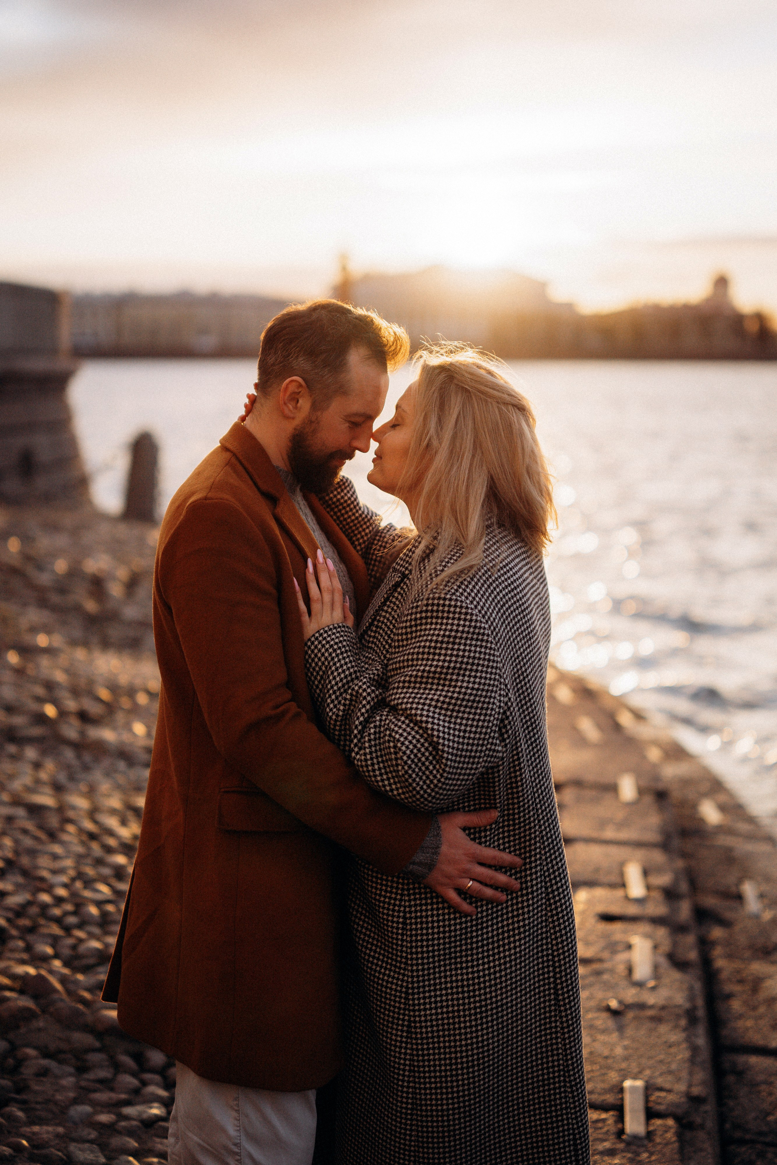 Лавстори Love Story в Санкт-Петербурге у набережной Невы на закате. Пара смотрит друг на друга в лучах заходящего солнца.