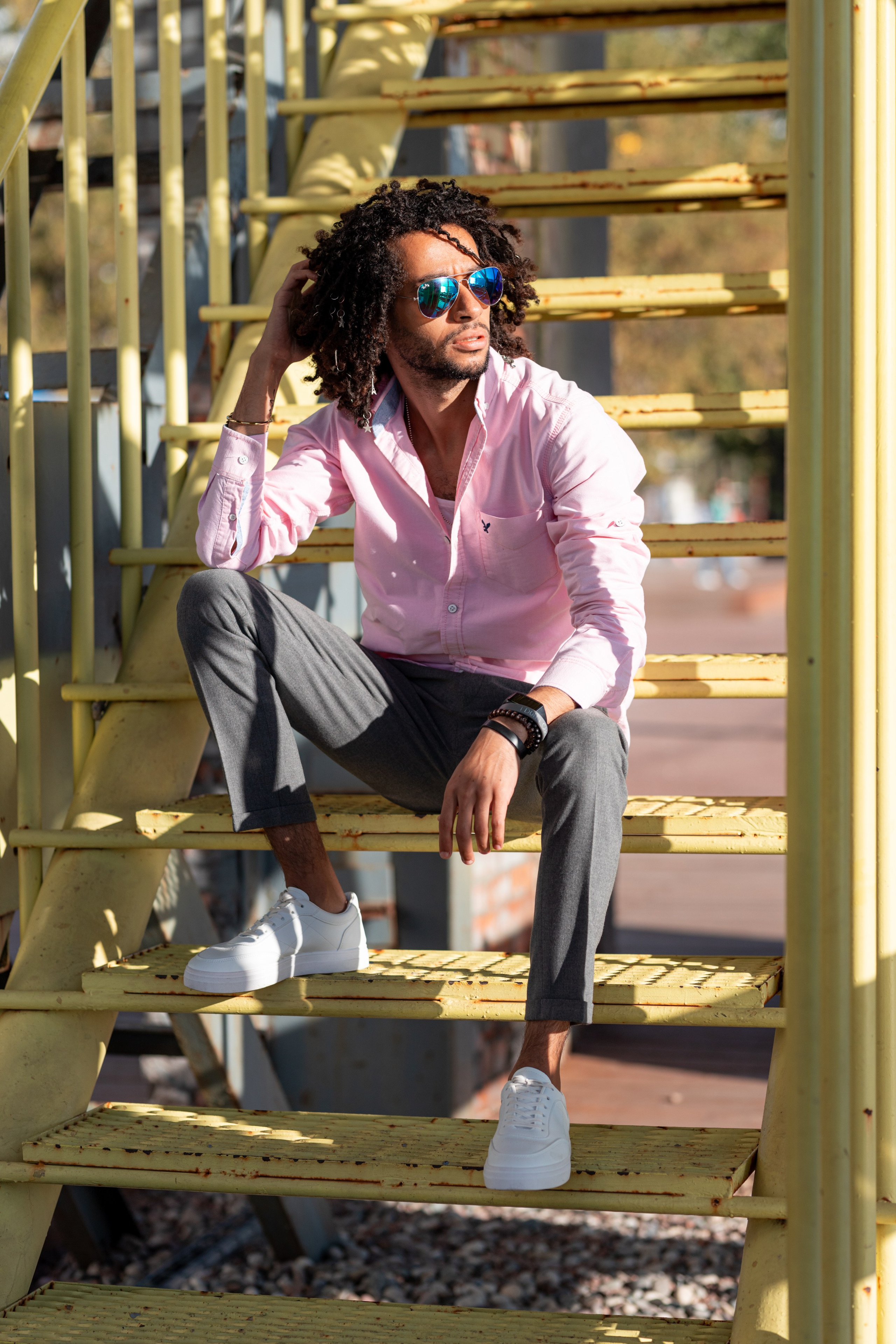 Темнокожий мужчина в солнечных очках сидит на лестнице