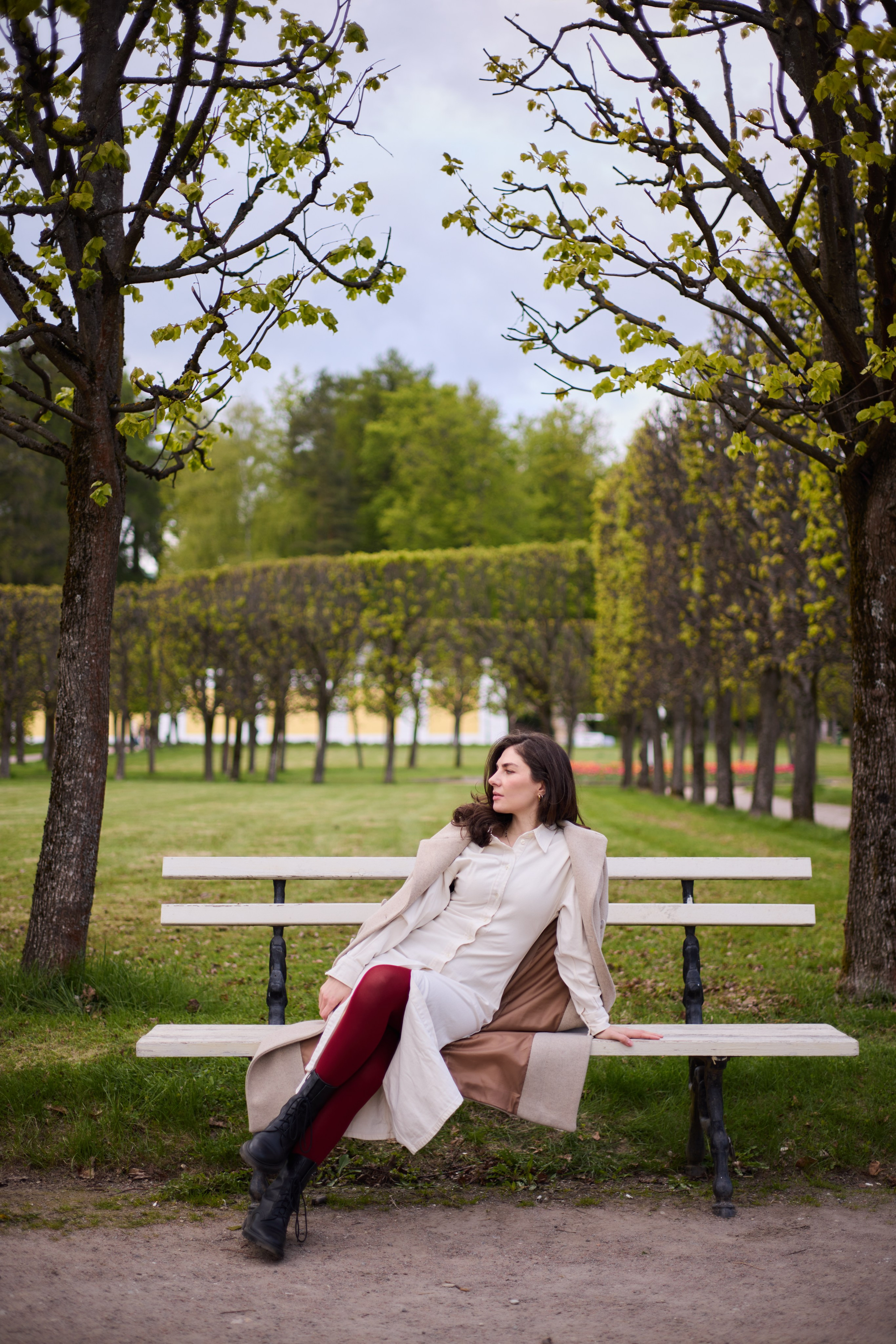 Фотосессия в Архангельском с Астой Габлия в белом платье и бежевом пальто, с красными колготками сидящей на скамейки
