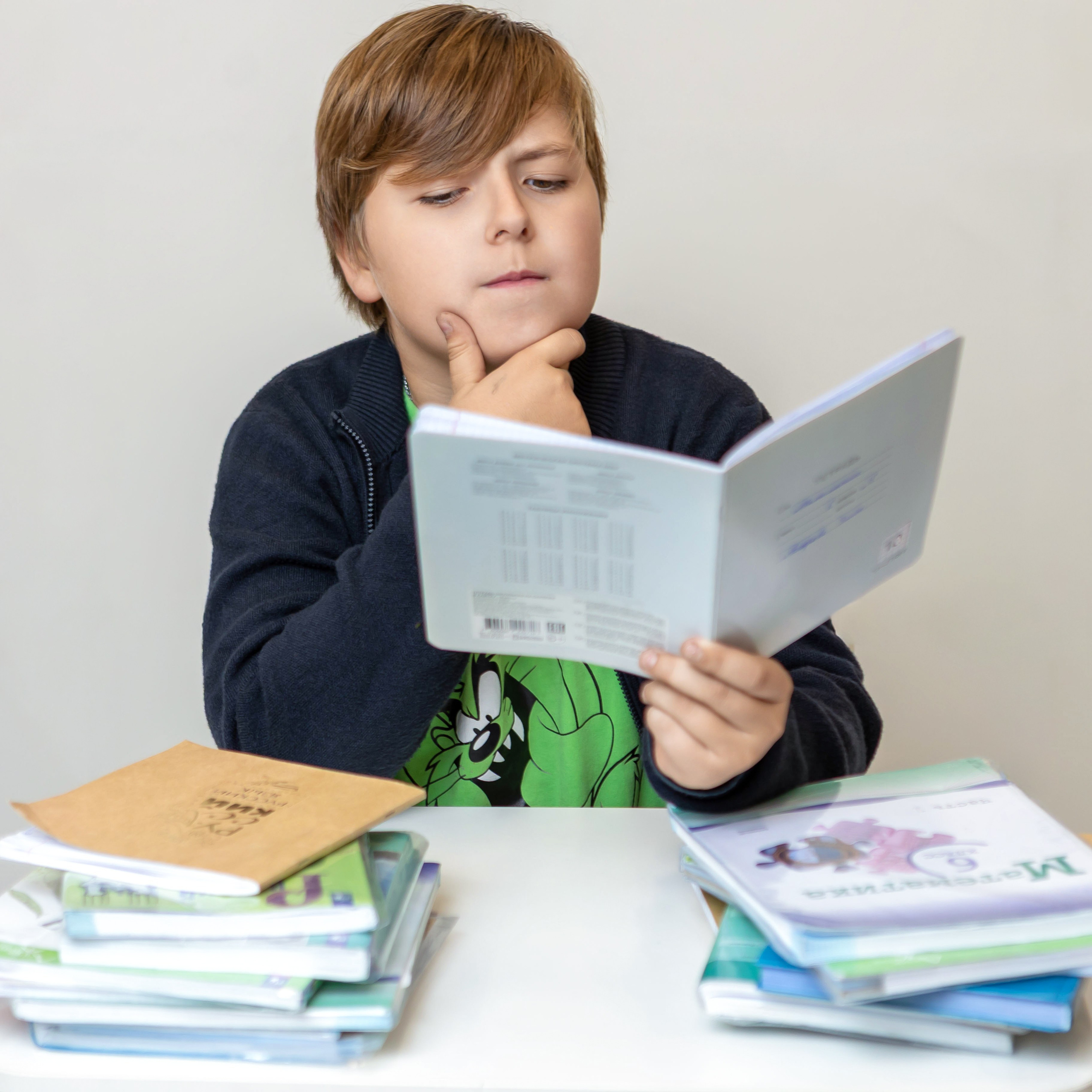 Мальчик за партой читает книгу, школьная фотосессия