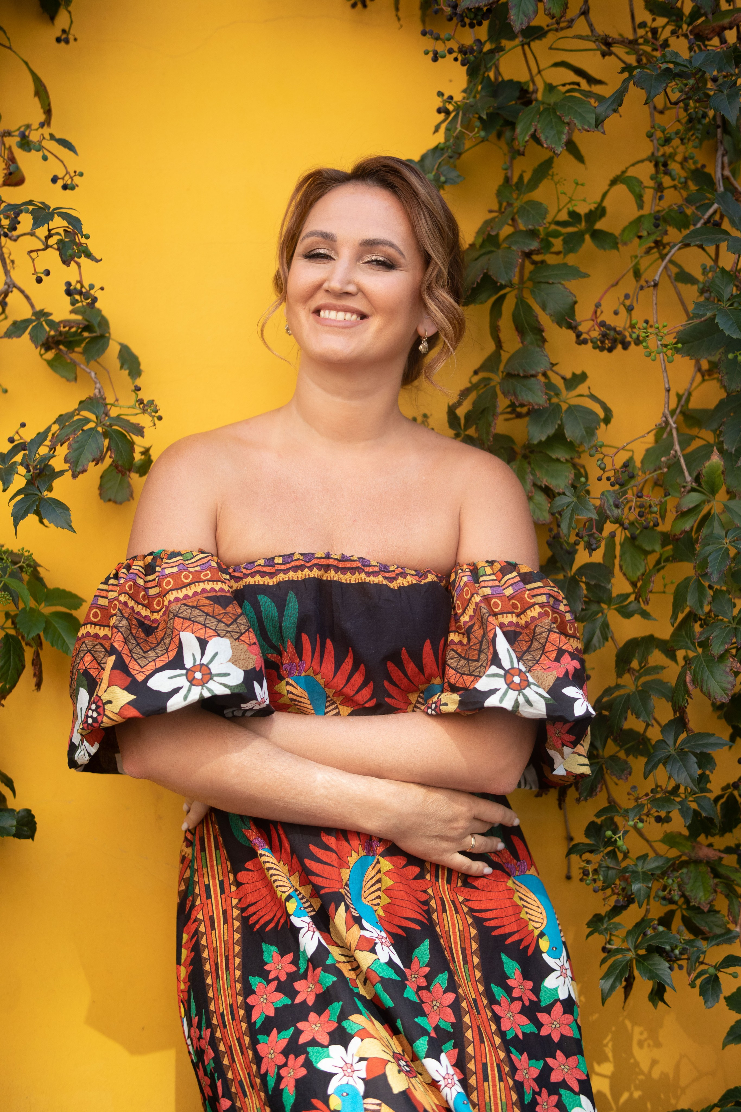 женщина в цветастом платье на фоне желтой стены