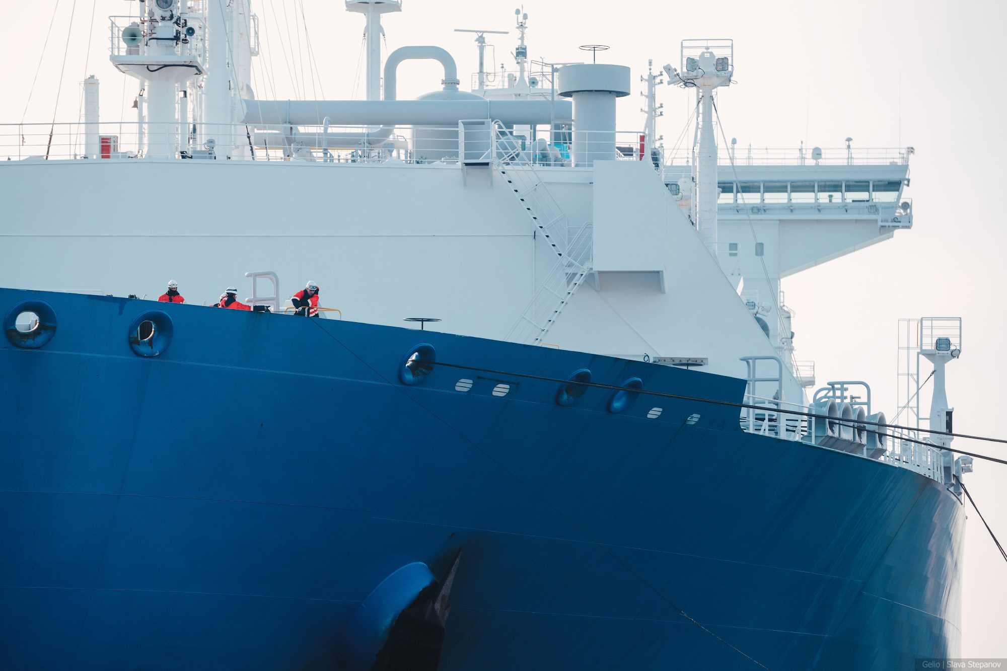 Крупный план палубы современного газовоза, моряки в спецодежде работают с швартовыми концами на борту огромного судна, Gelio