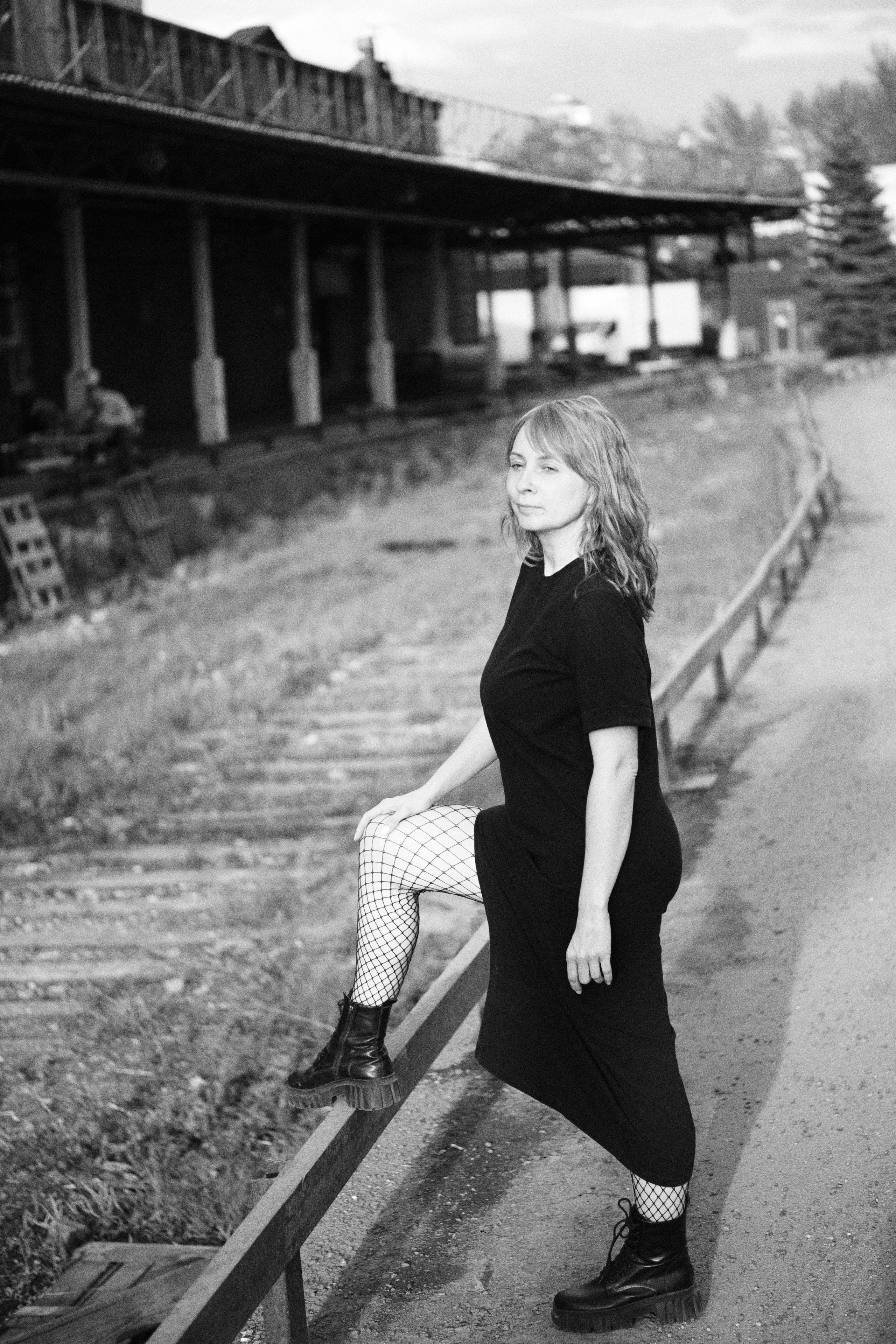 Женщина стоит, поставив ногу на перилу