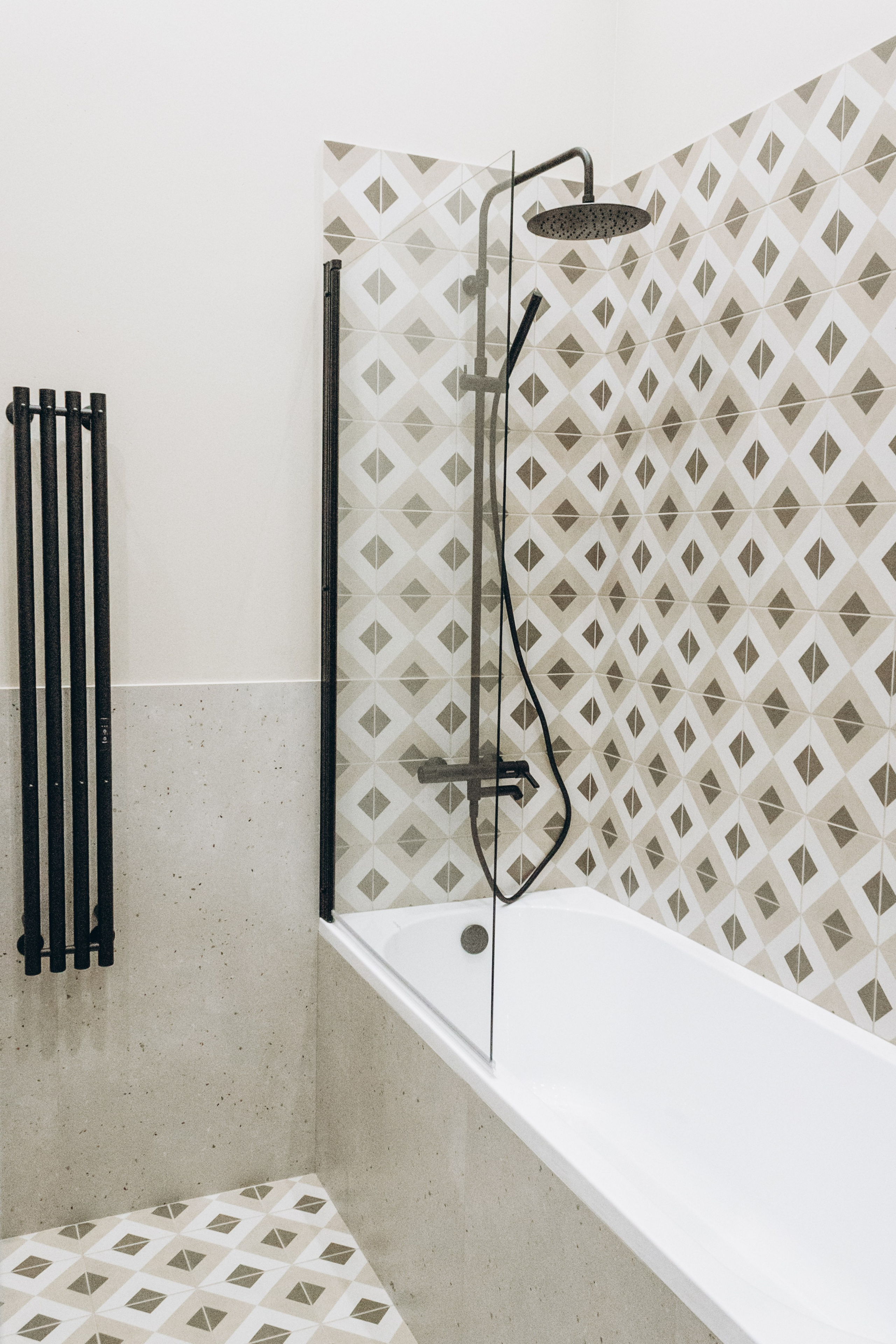 Интерьер ванной комнаты  с мраморной отделкой и черными вертикальными радиаторами