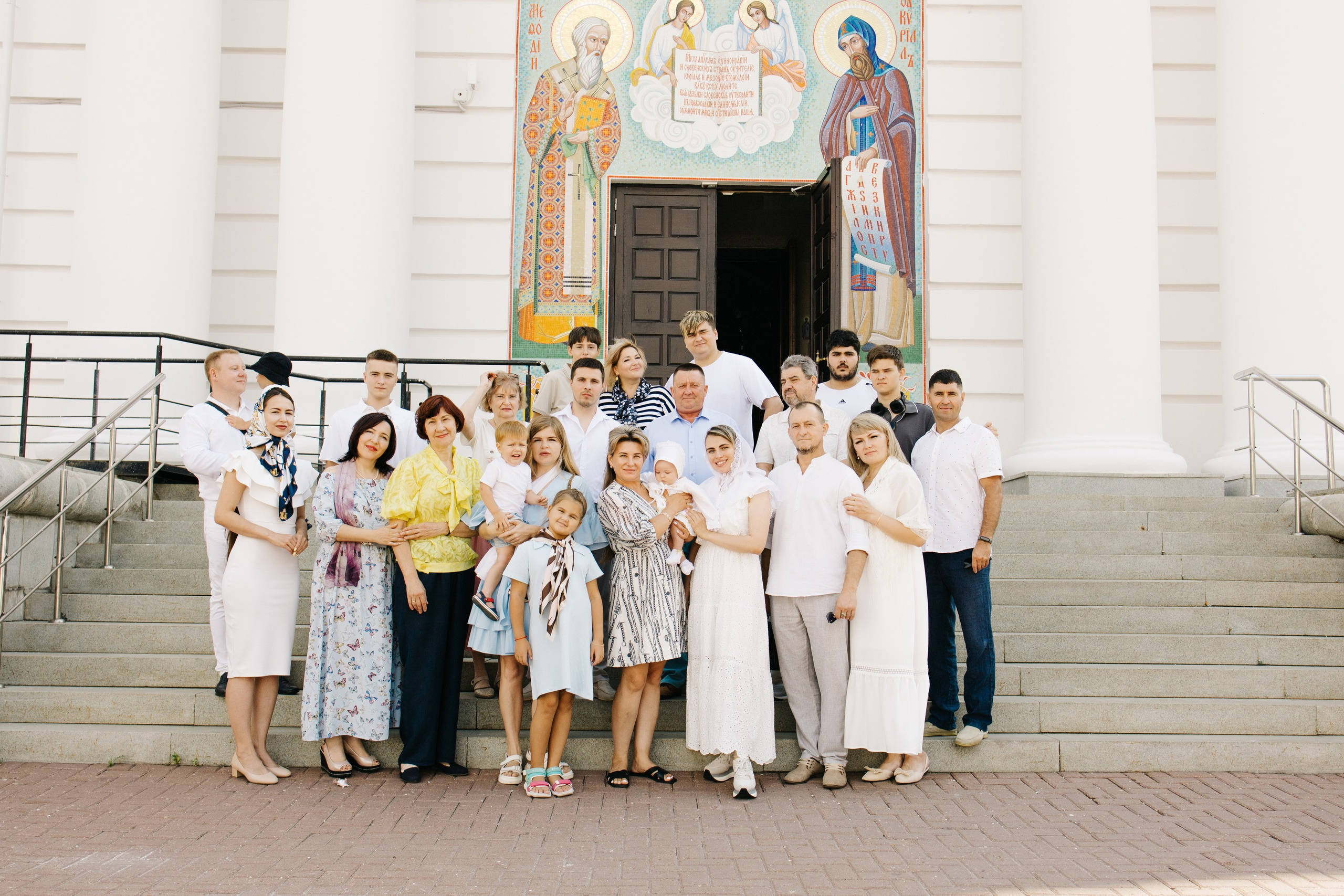 большая семья на ступеньках храма перед таинством крещения