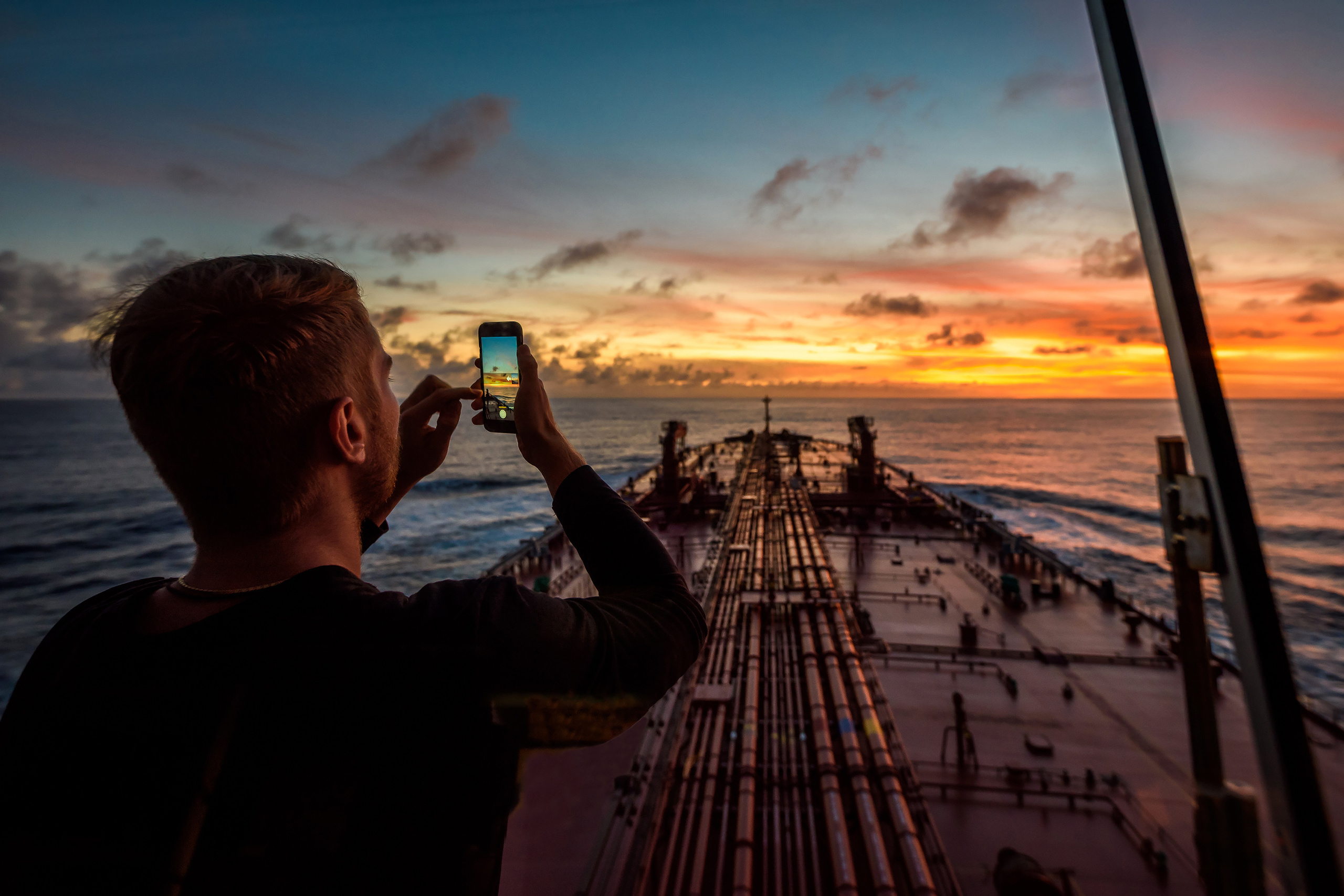 Моряк фотографирует закат на борту танкера