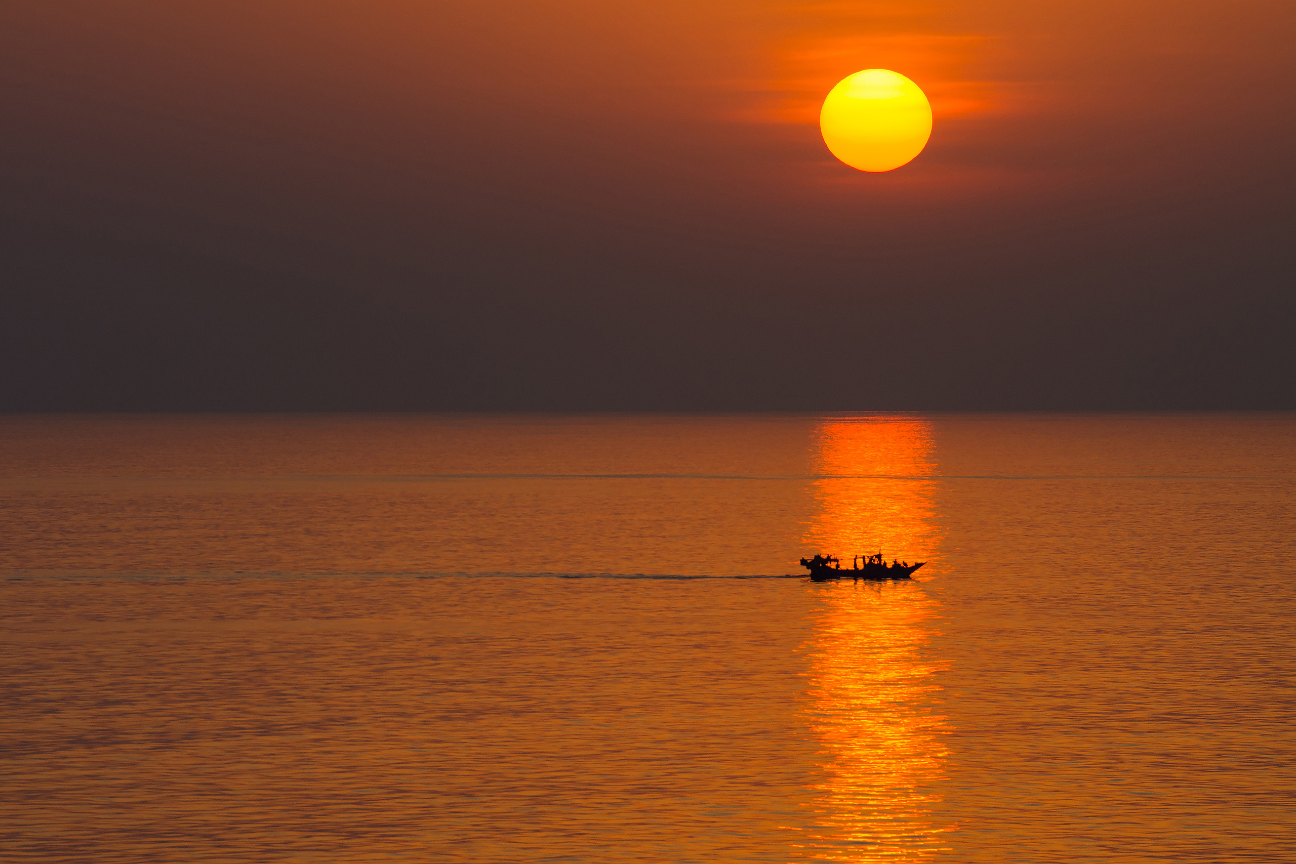 Рыбацкое судно на золотой дорожке заката