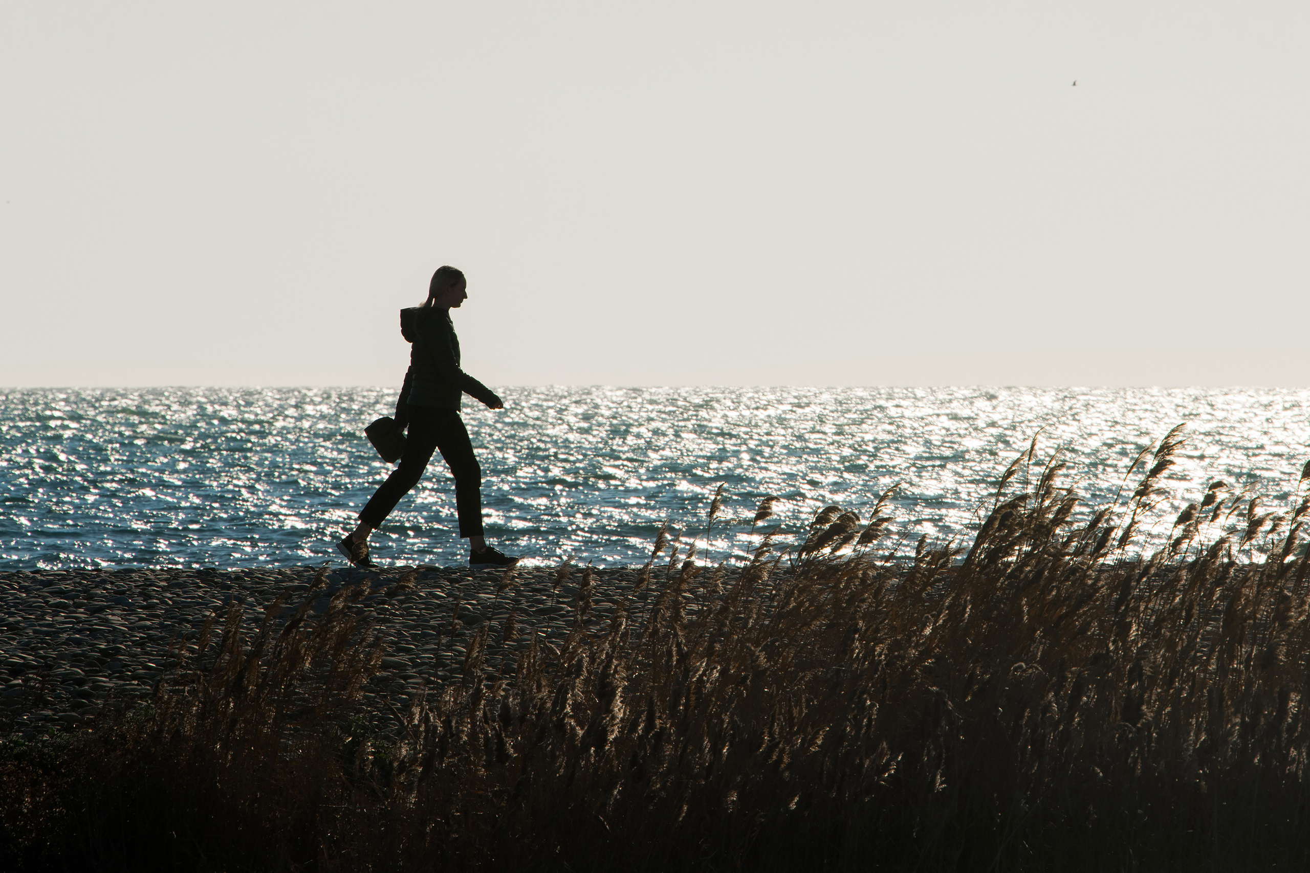 Силуэт девушки с сумочкой, идущей по пляжу, Новороссийск