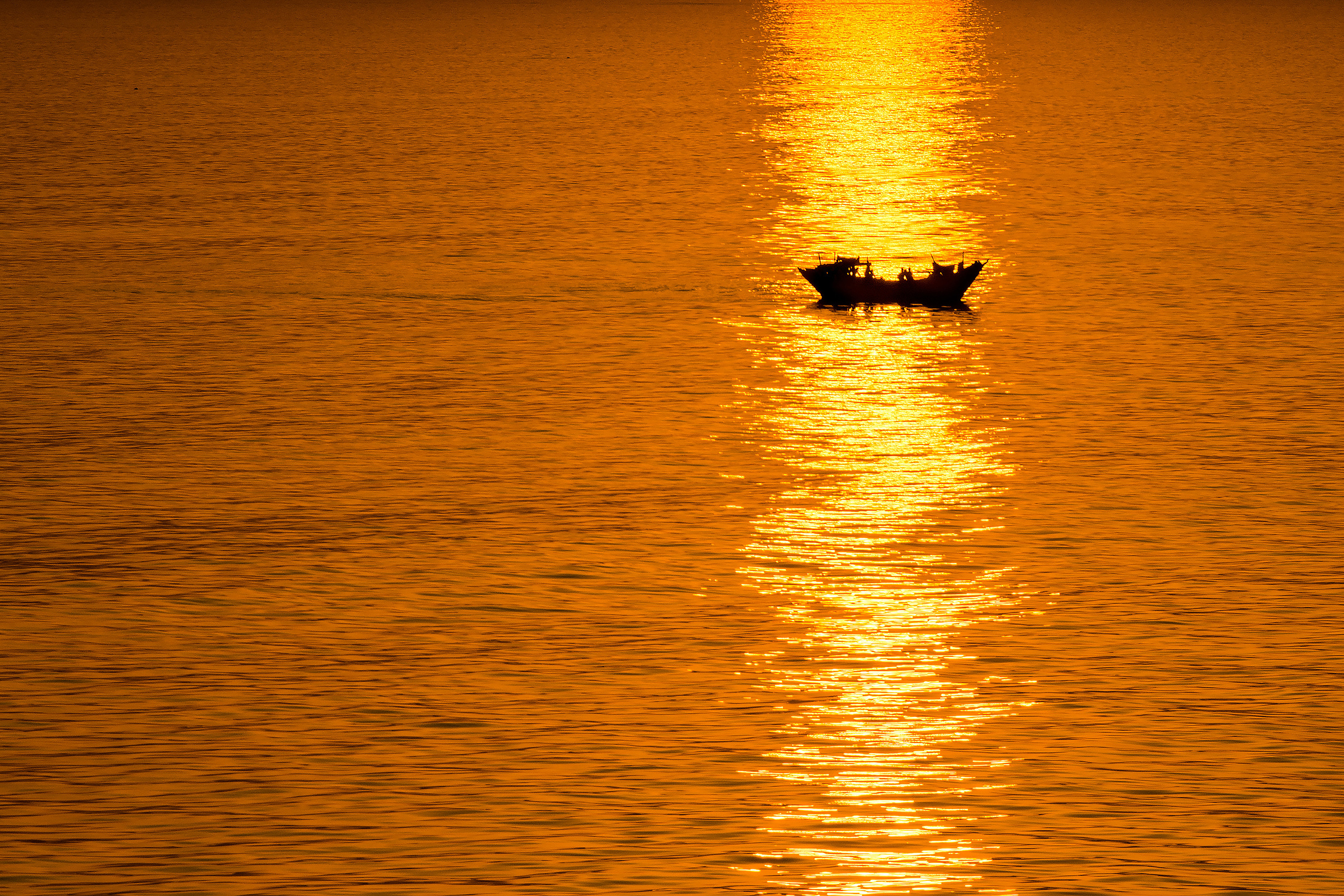 Рыболовное судно на золотистой дорожке на поверхности океана