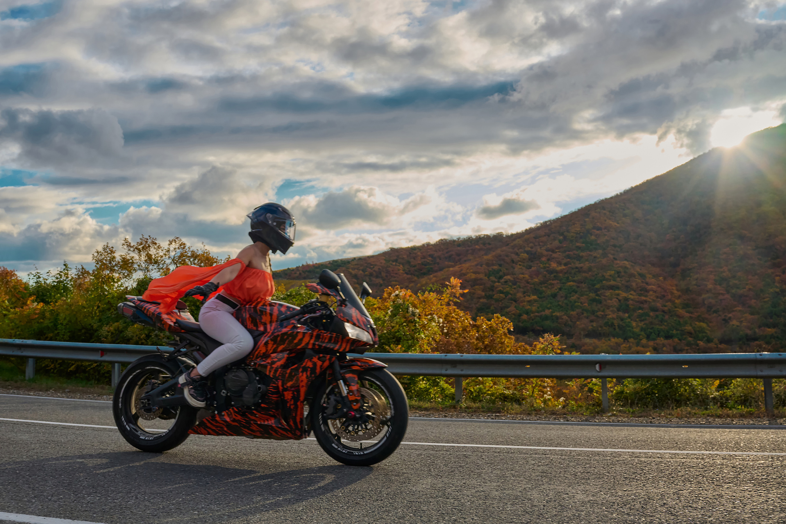 Девушка в оранжевом топе на мотоцикле