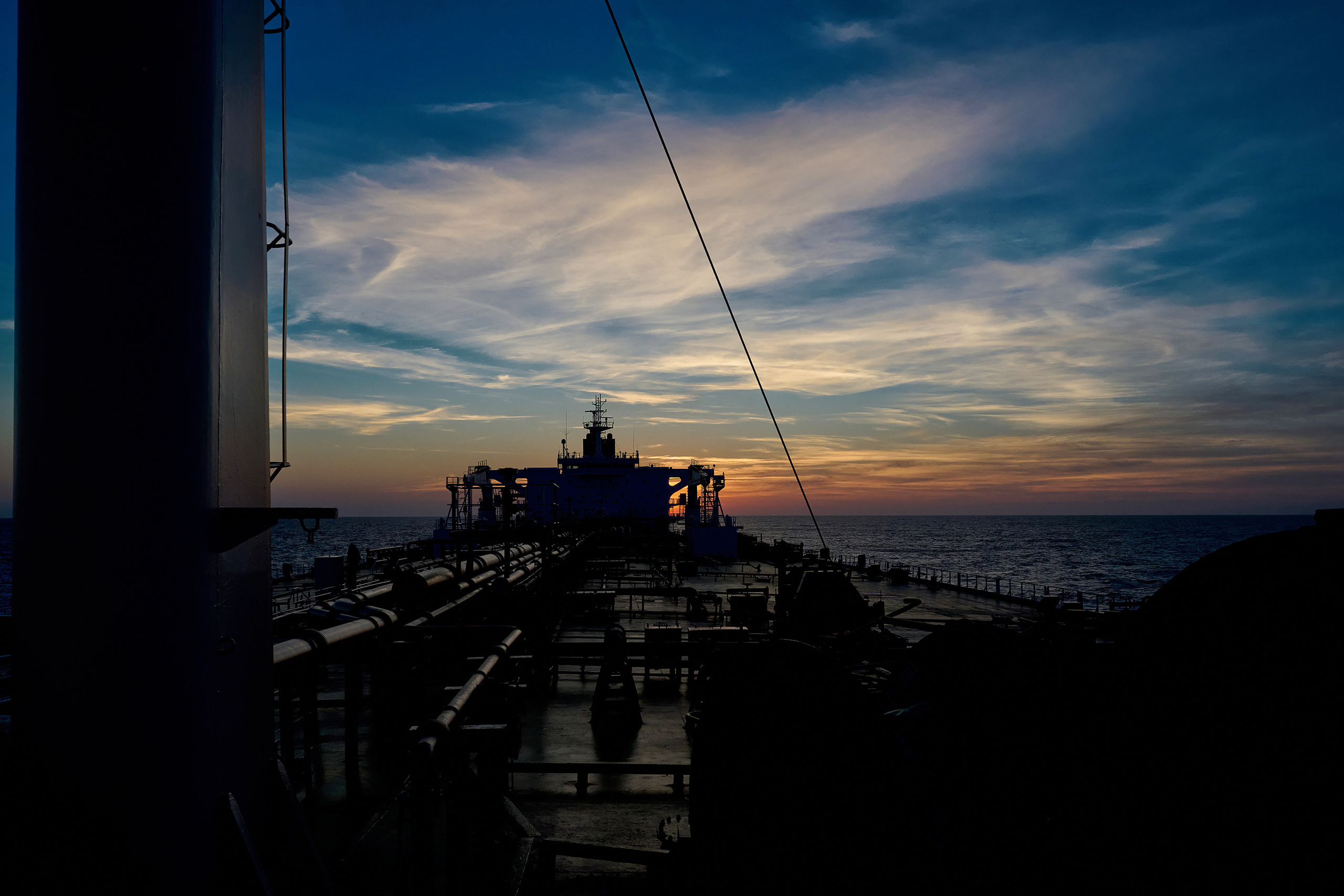 Вид, силуэт танкера с носовой части, на фоне заката